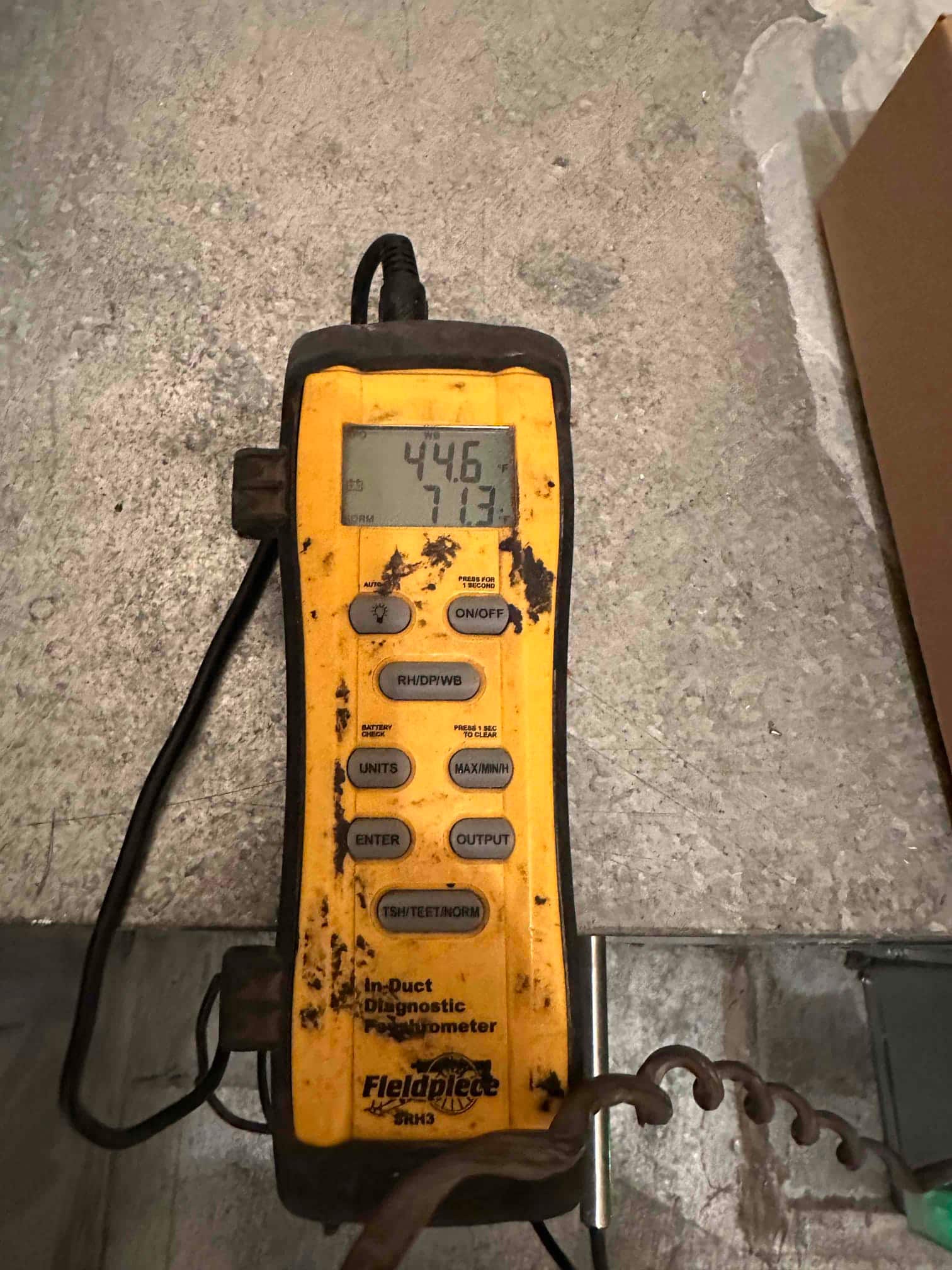 Digital thermometer displays 44.6 degrees Fahrenheit, documenting cold supply air temperature during system commissioning.