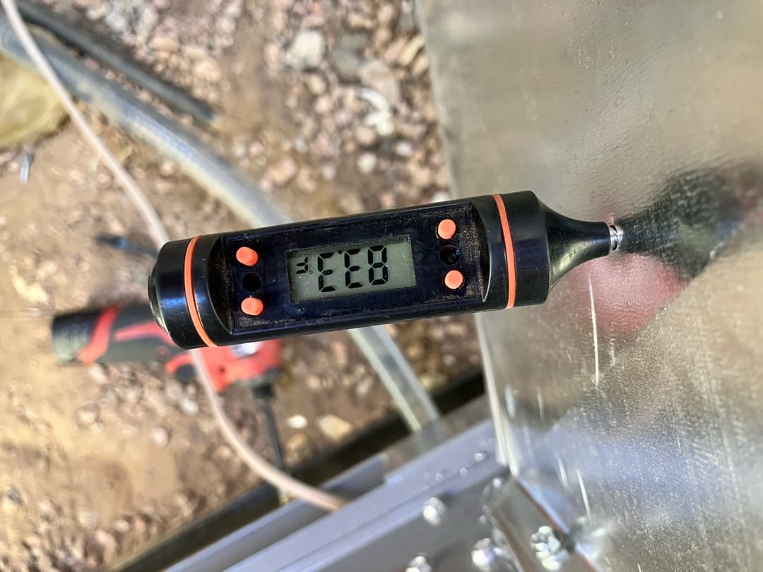 Digital thermometer probe inserted into sheet metal duct, display reading 55 degrees Fahrenheit for supply air temperature.