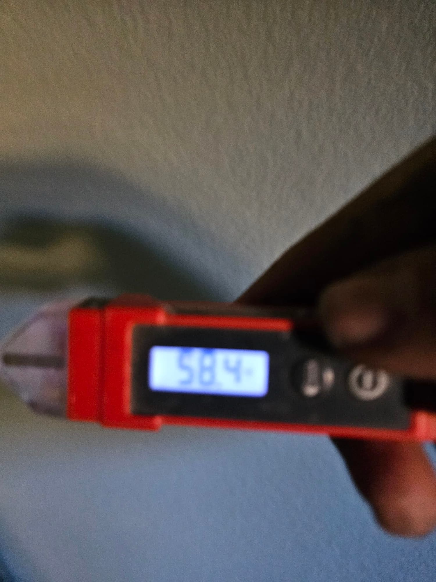 Digital thermometer probe shows 58 degrees Fahrenheit while measuring air temperature during system commissioning.