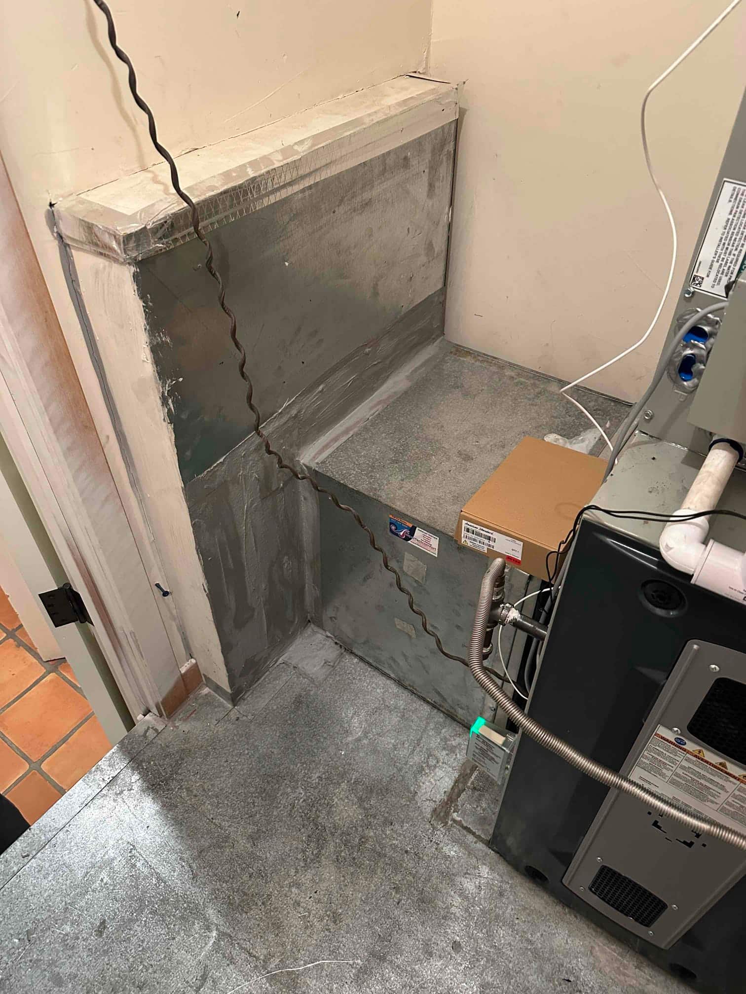Indoor furnace installed on a metal platform with sealed sheet-metal return plenum and electrical whip connected.