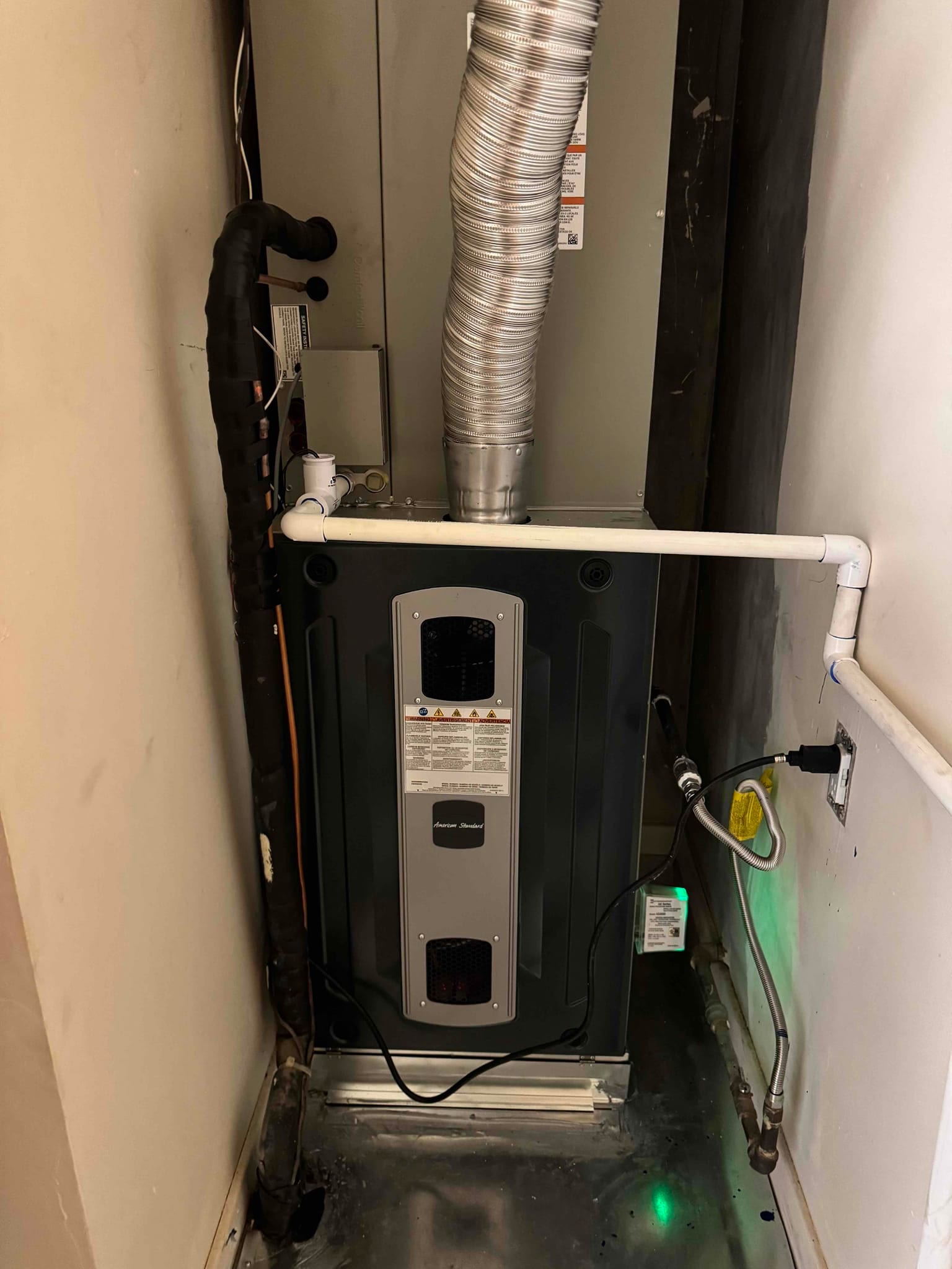 New gas furnace and evaporator coil installed with vent connector, condensate drain, insulated refrigerant line, and gas flex connector.