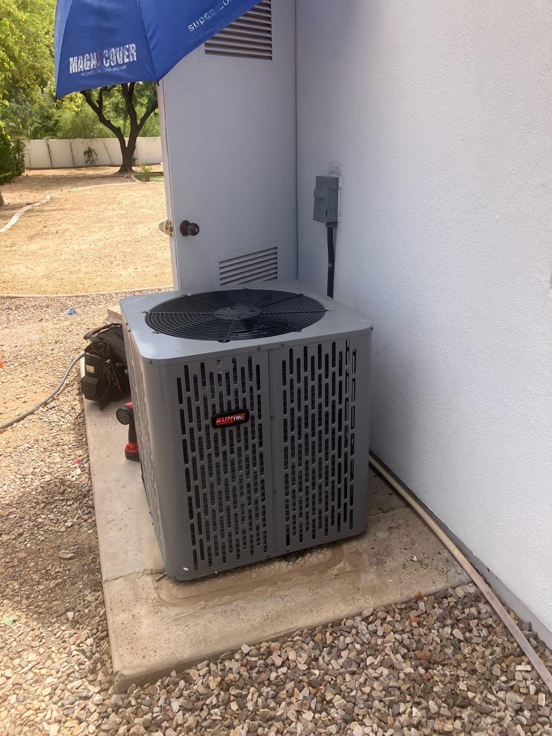 New outdoor condenser set on a level pad with nearby disconnect and insulated refrigerant line routed along the wall.