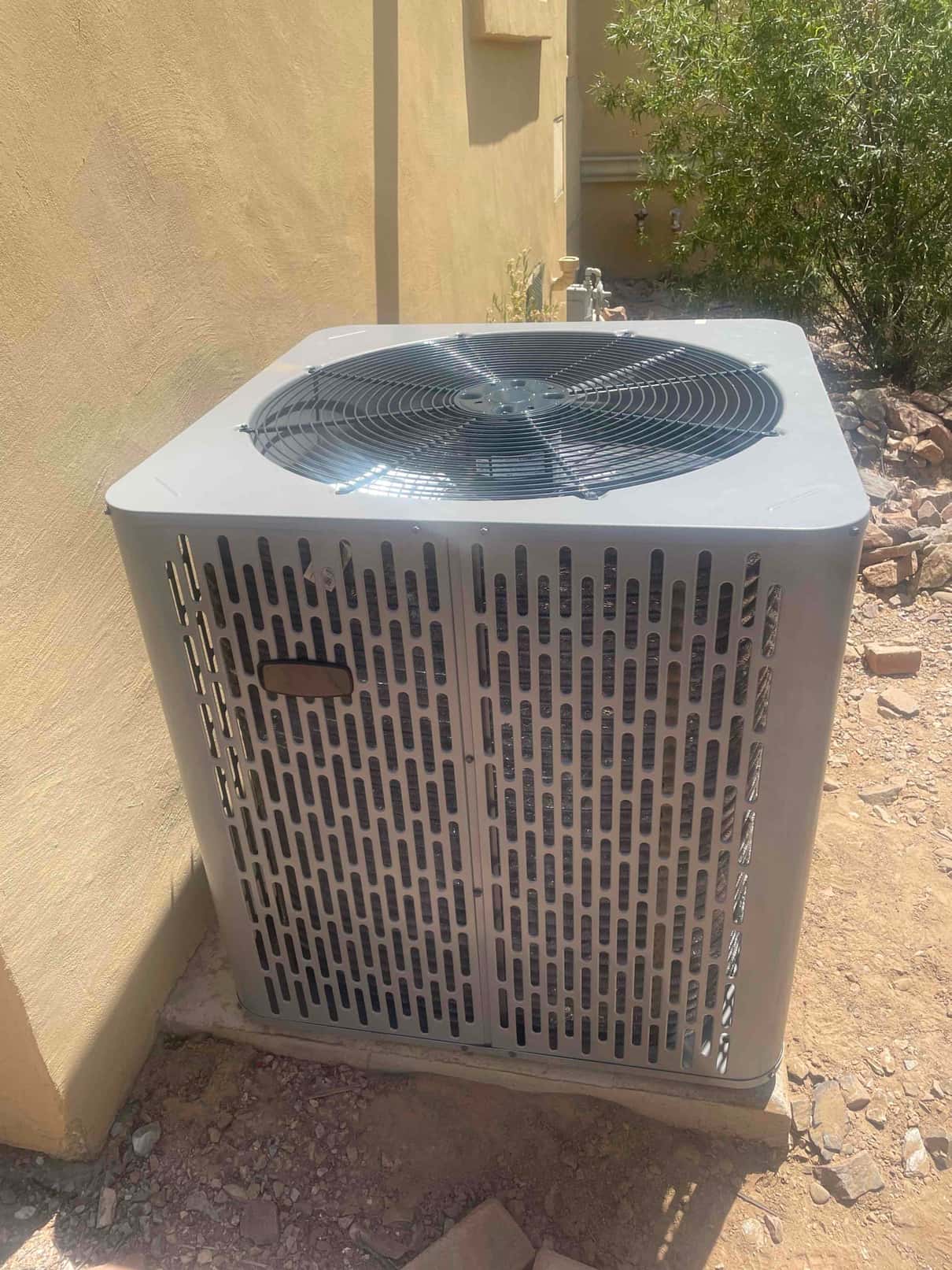 New outdoor heat pump condenser set on a level pad beside the house with proper clearance around the unit.