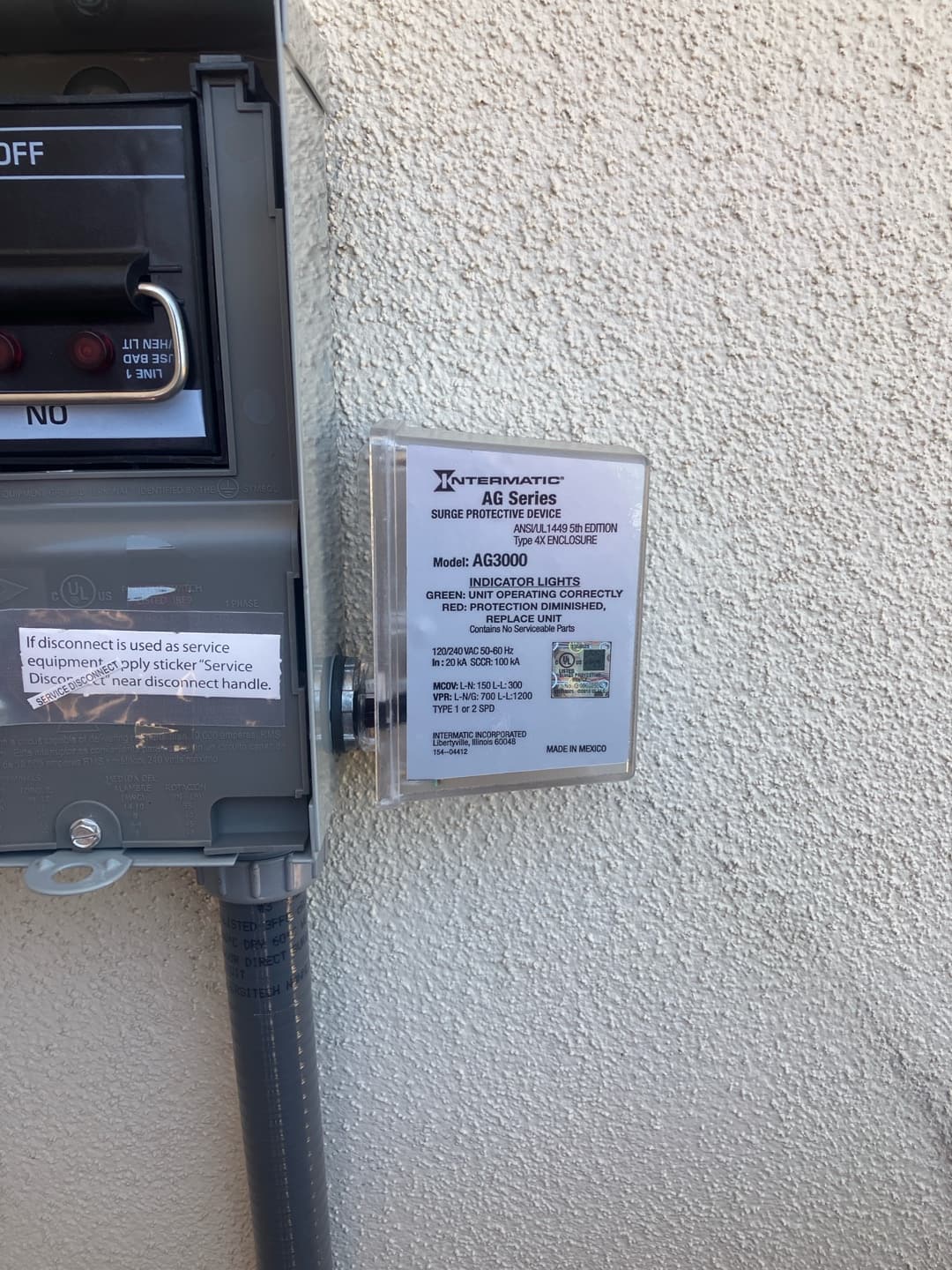 Outdoor HVAC disconnect with installed surge protective device mounted on the wall beside the conduit.