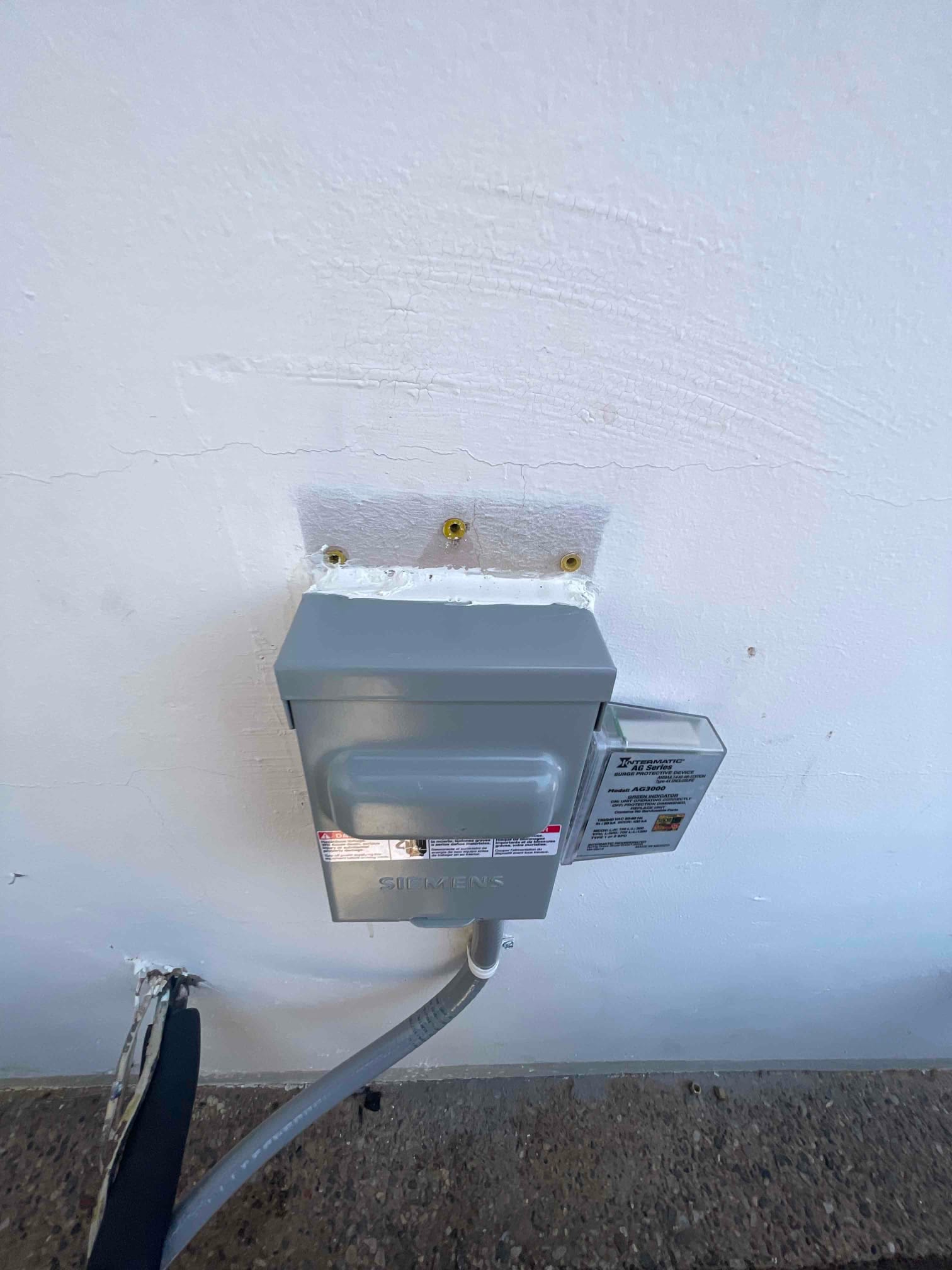 Outdoor HVAC disconnect with surge protector installed on exterior wall, sealed penetrations, and flexible conduit routed to the condenser location.