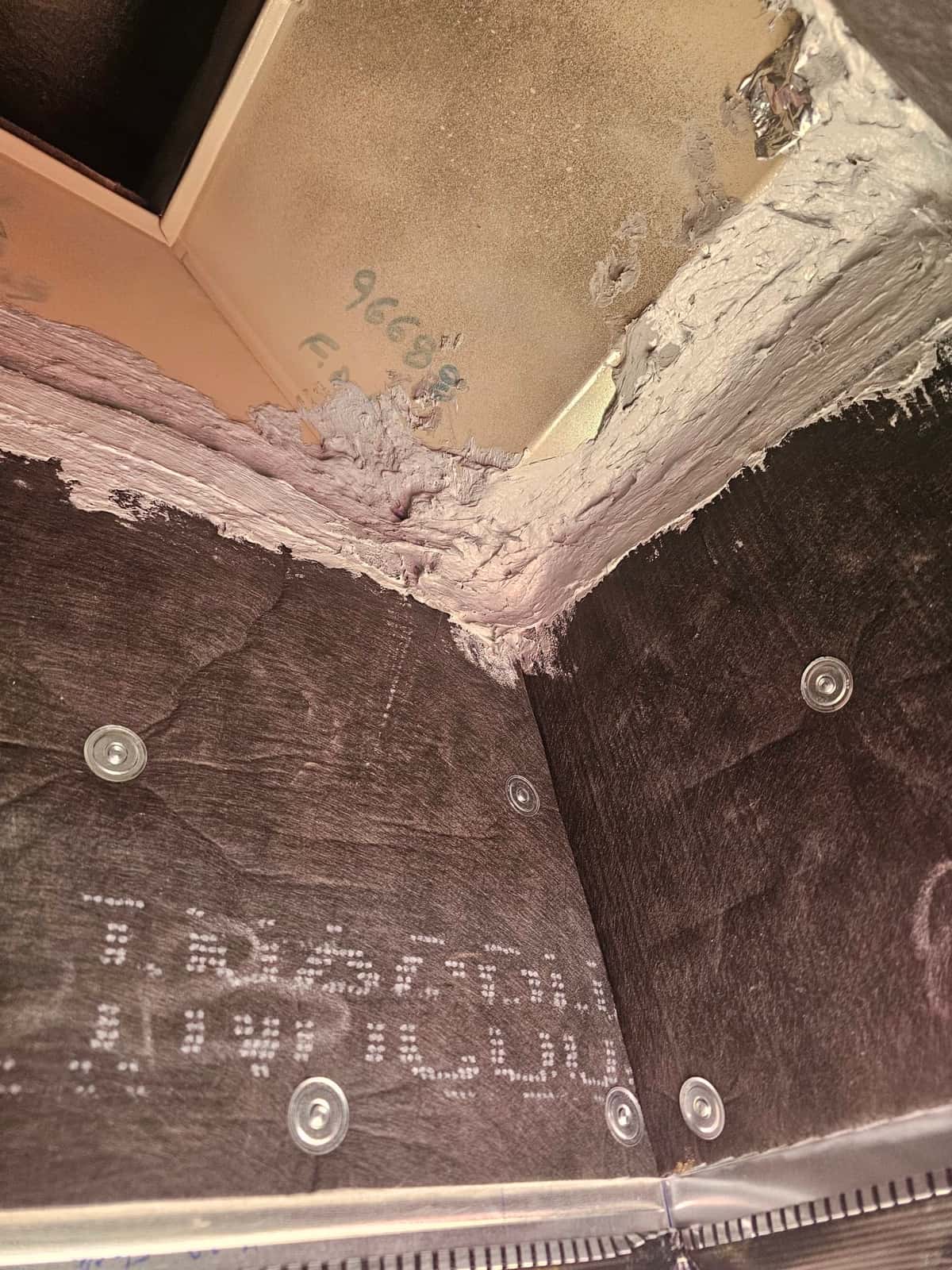 Sealed duct transition with mastic applied around joints and fasteners, showing newly assembled sheet metal and liner panels.