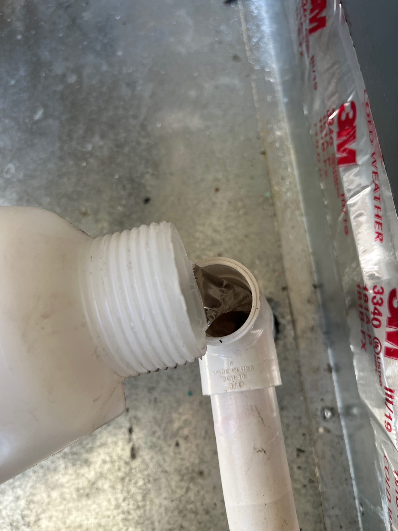 Technician pours cleaner into the air handler’s condensate drain cleanout to clear buildup and improve drainage.