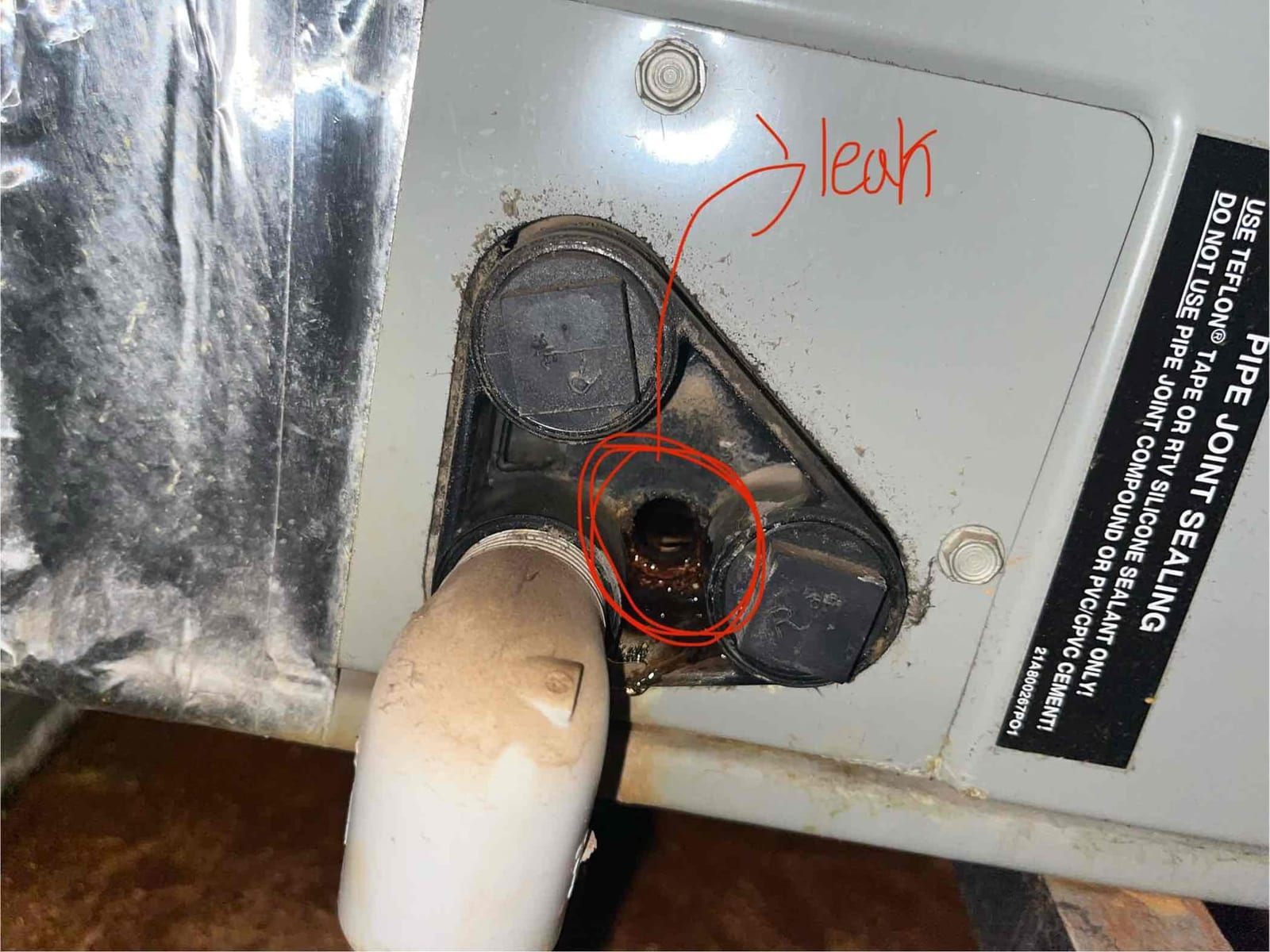 Air handler condensate drain connection showing brown water and residue leaking from the rubber grommet area.