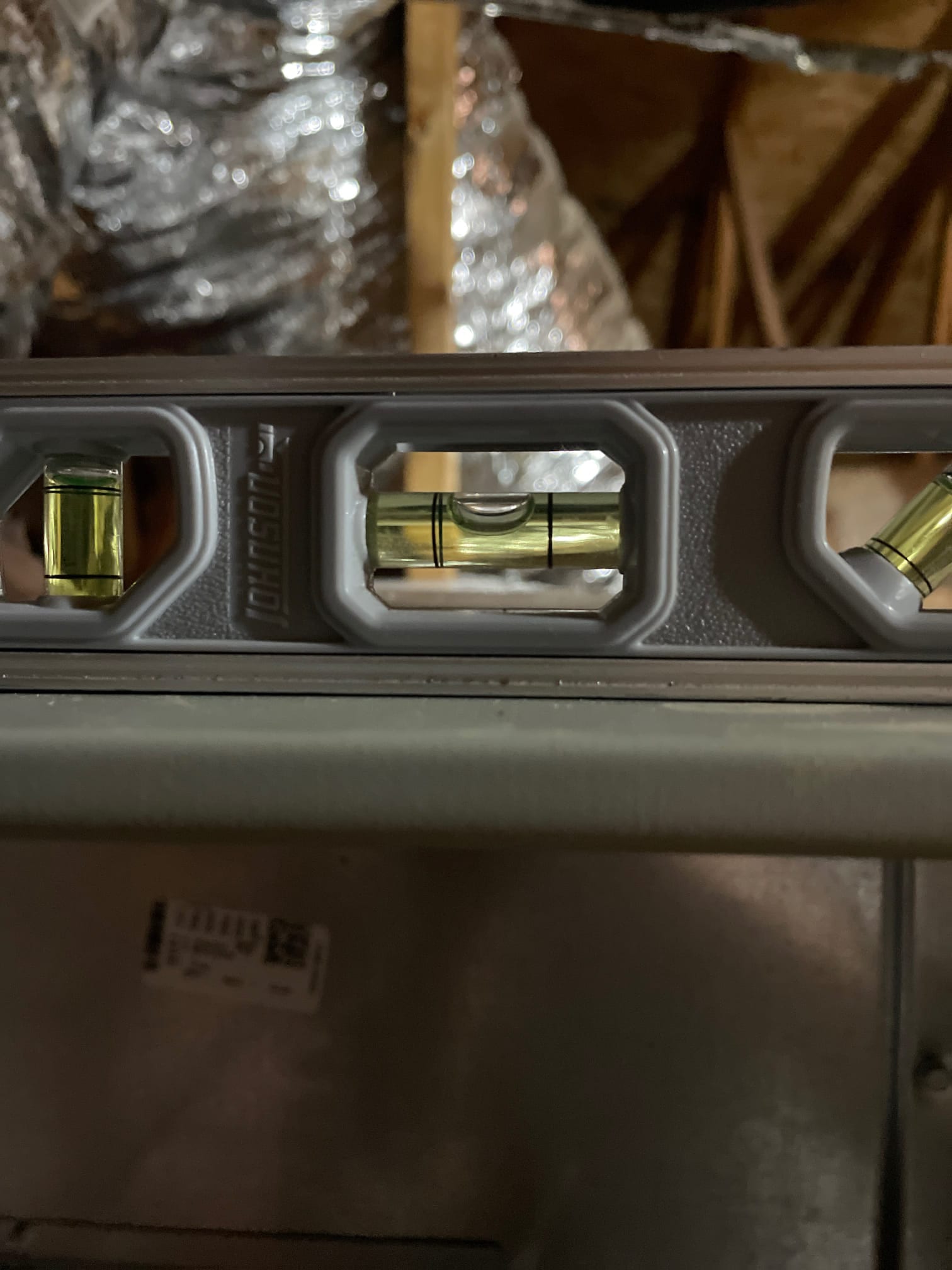 Bubble level placed on the air handler cabinet shows the unit set level during installation in the attic.