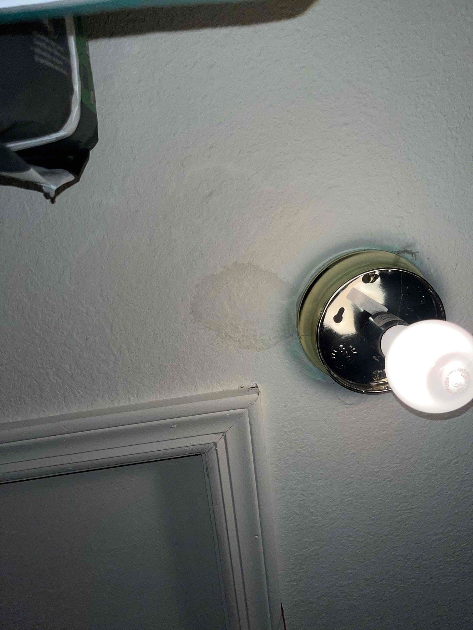 Ceiling drywall shows a circular water stain near a light fixture, indicating moisture intrusion from above.