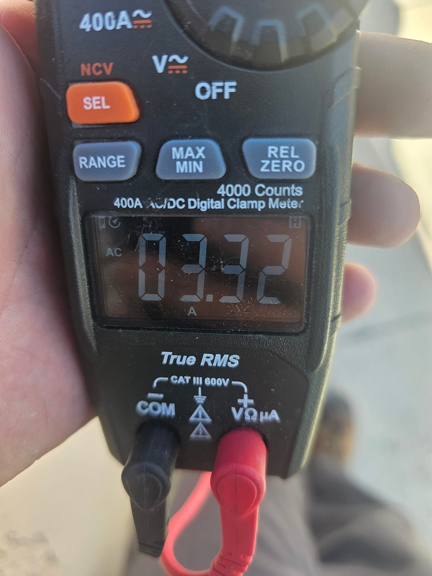 Clamp meter displays 0.32 A AC current with test leads connected to the COM and V inputs.