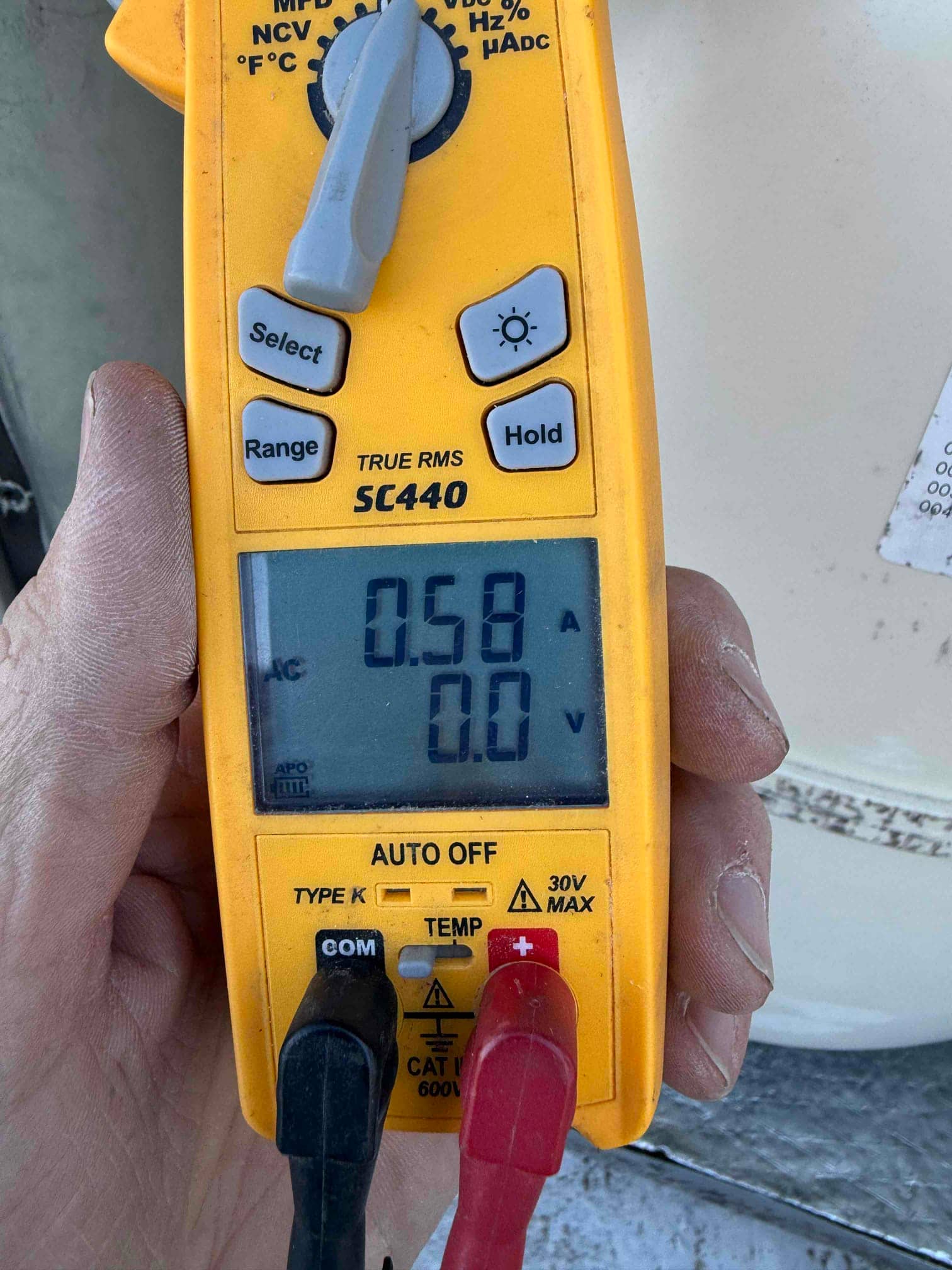 Clamp meter displays 0.58 A on the conductor, with meter leads connected but not measuring voltage.