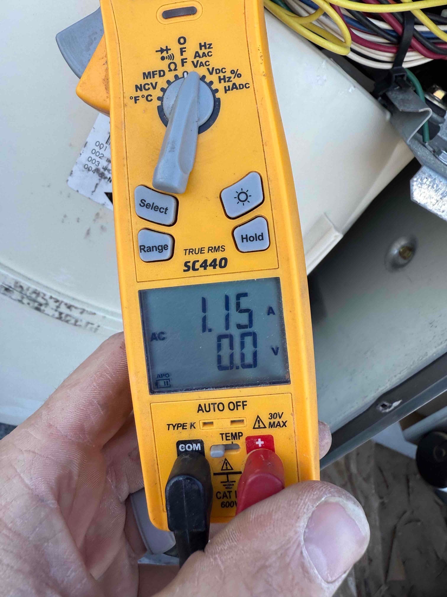 Clamp meter displays 1.15 A AC on a clamped conductor, with test leads inserted but not in use.