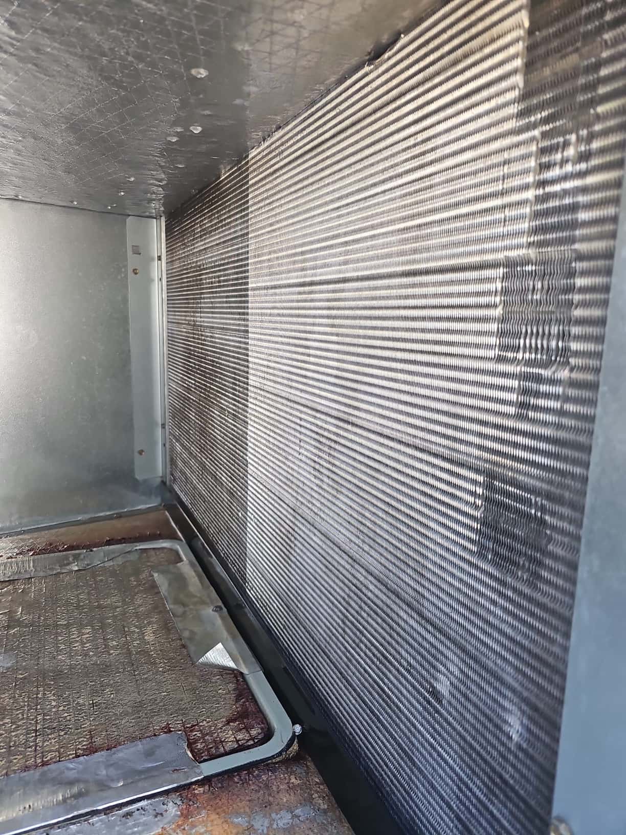 Clean evaporator coil fins inside the air handler cabinet, showing uniform fin spacing and no visible debris or buildup.