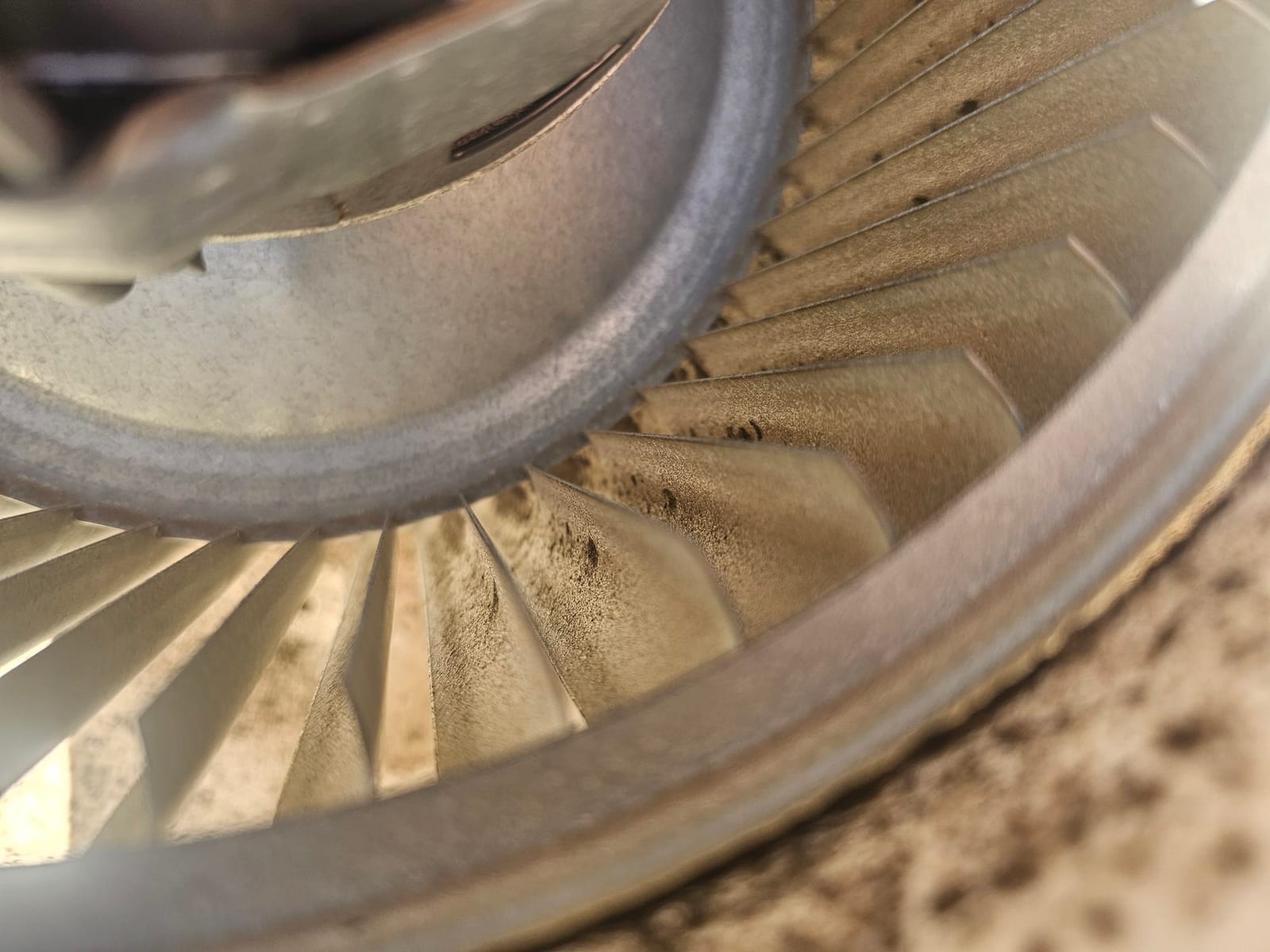 Close-up of a blower wheel with dust accumulation on the blades prior to cleaning.