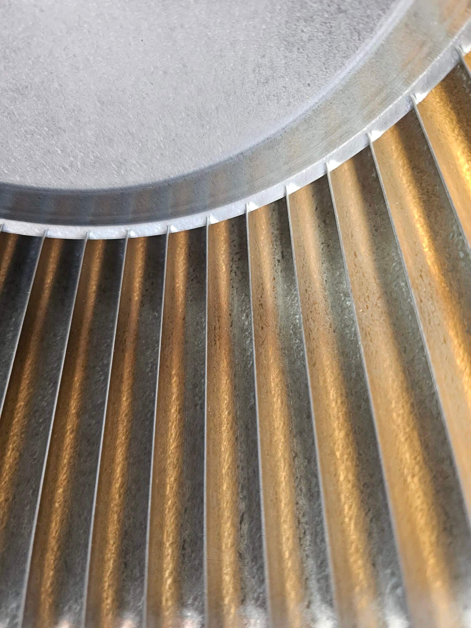 Close-up of a clean metal blower wheel with evenly spaced fins inside the air handler housing.