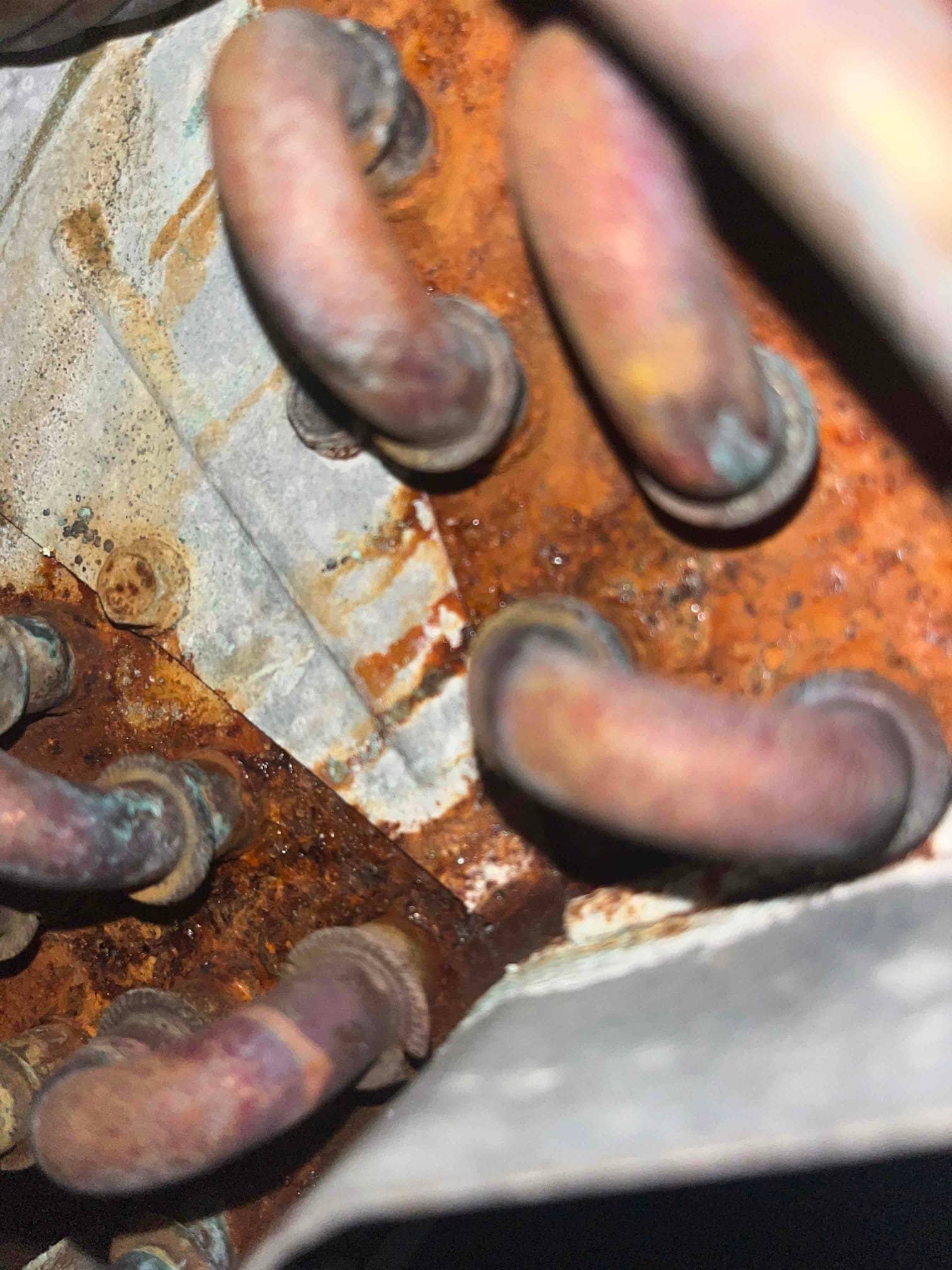 Close-up of corroded copper refrigerant tubing and rusted metal surface inside an air conditioning component.