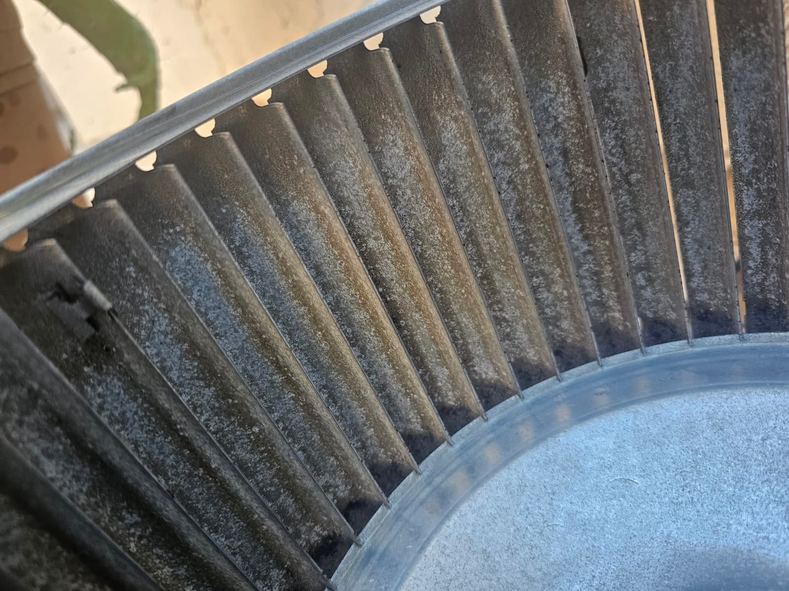 Close-up of a dirty blower wheel with dust buildup on the blades before cleaning during air conditioning repair.
