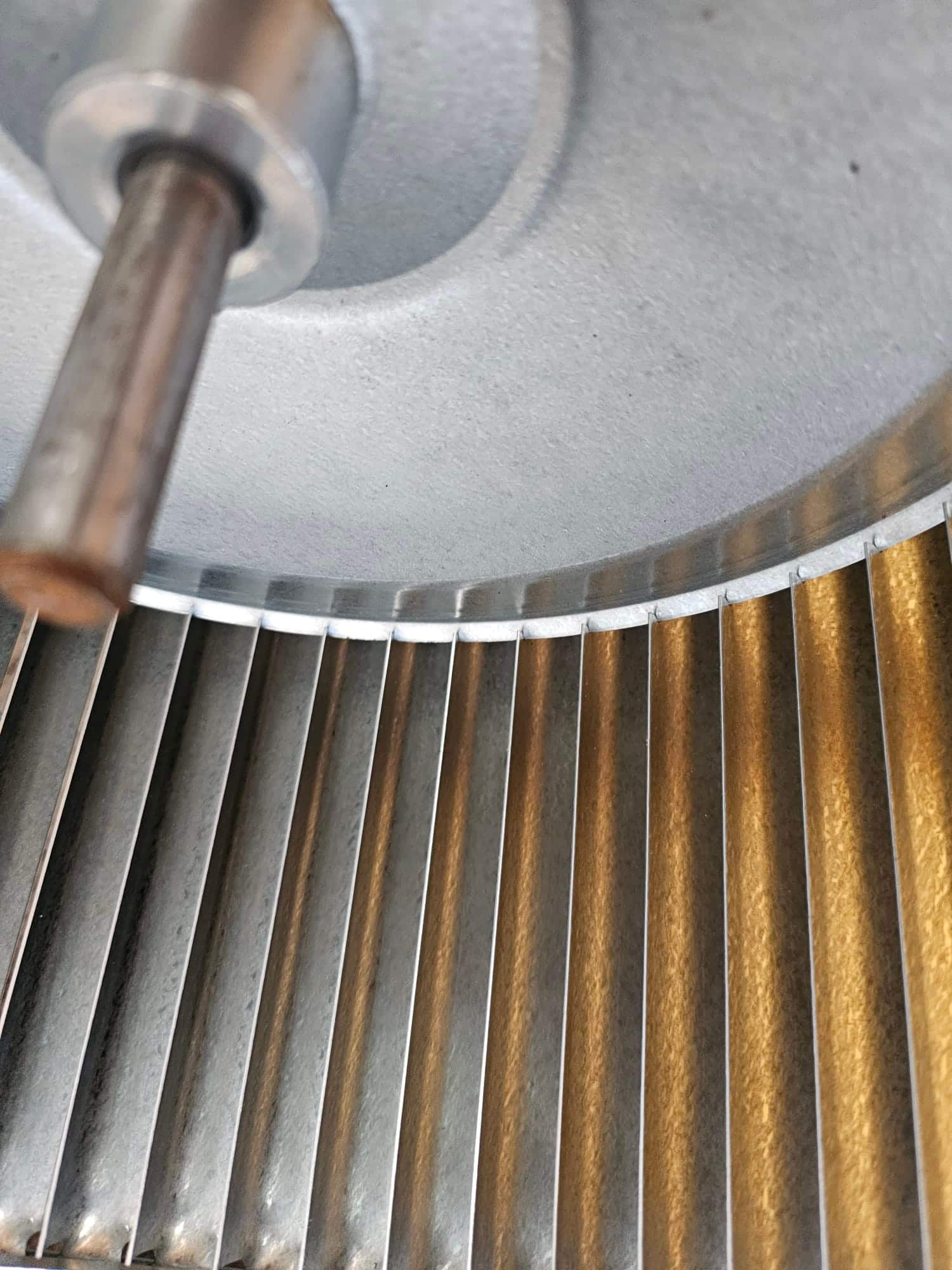 Close-up of an HVAC blower wheel, showing clean metal fins and central hub after service.
