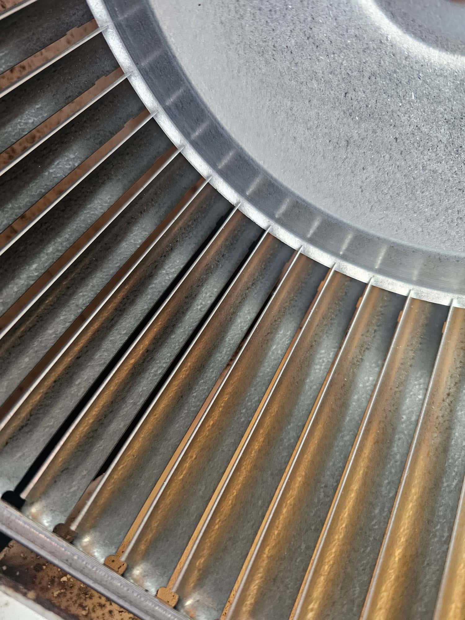 Close-up of an HVAC blower wheel showing dust accumulation on the blades before cleaning during repair.