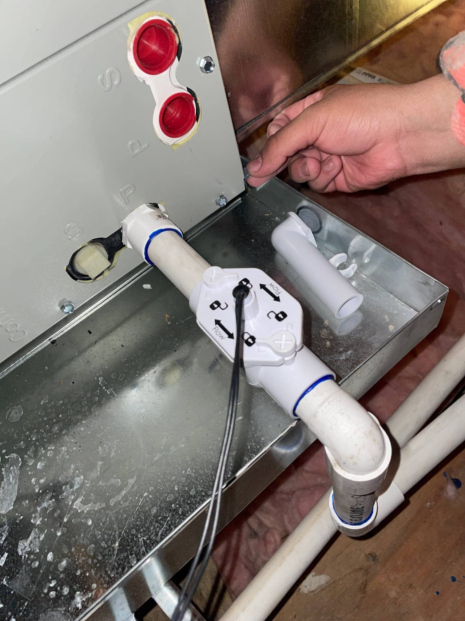Condensate drain assembly with float safety switch installed at the air handler, PVC piping connected and sealed at the drain port.