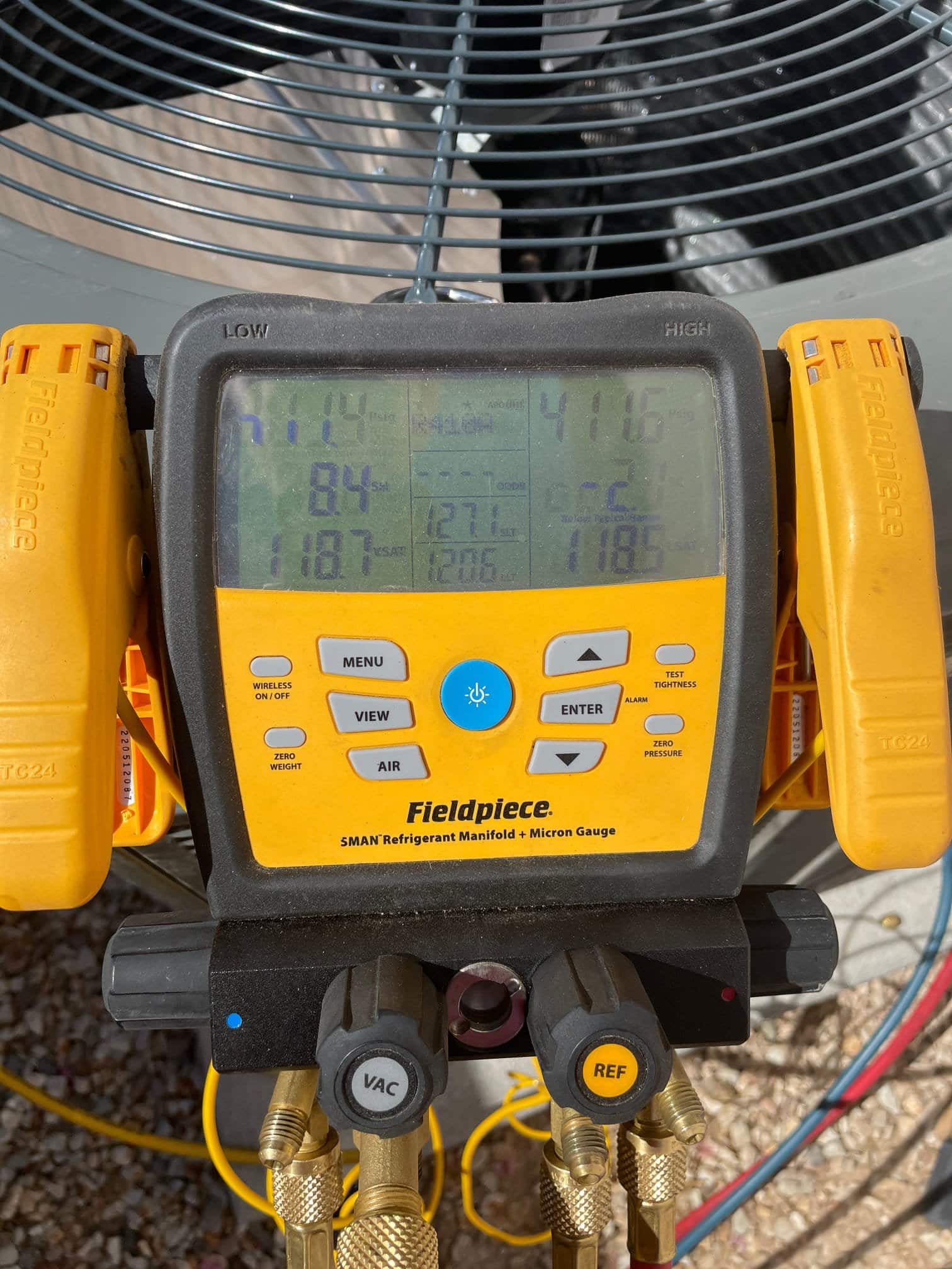 Digital manifold connected to the condenser shows operating pressures with the system running, documenting low and high side values during commissioning.