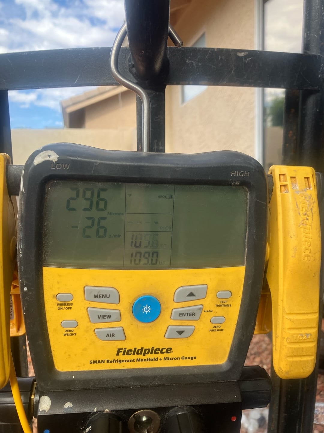 Digital micron gauge on the manifold shows 296 microns during system evacuation prior to refrigerant charging.
