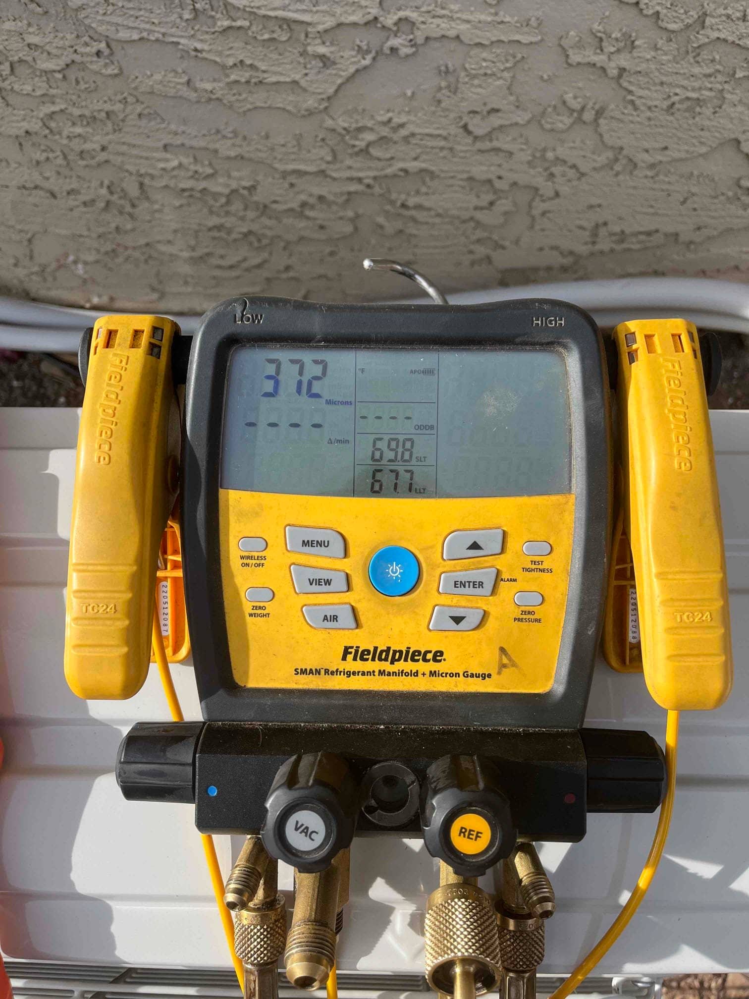 Digital micron gauge on the manifold shows 372 microns during evacuation, confirming a deep vacuum before releasing refrigerant.