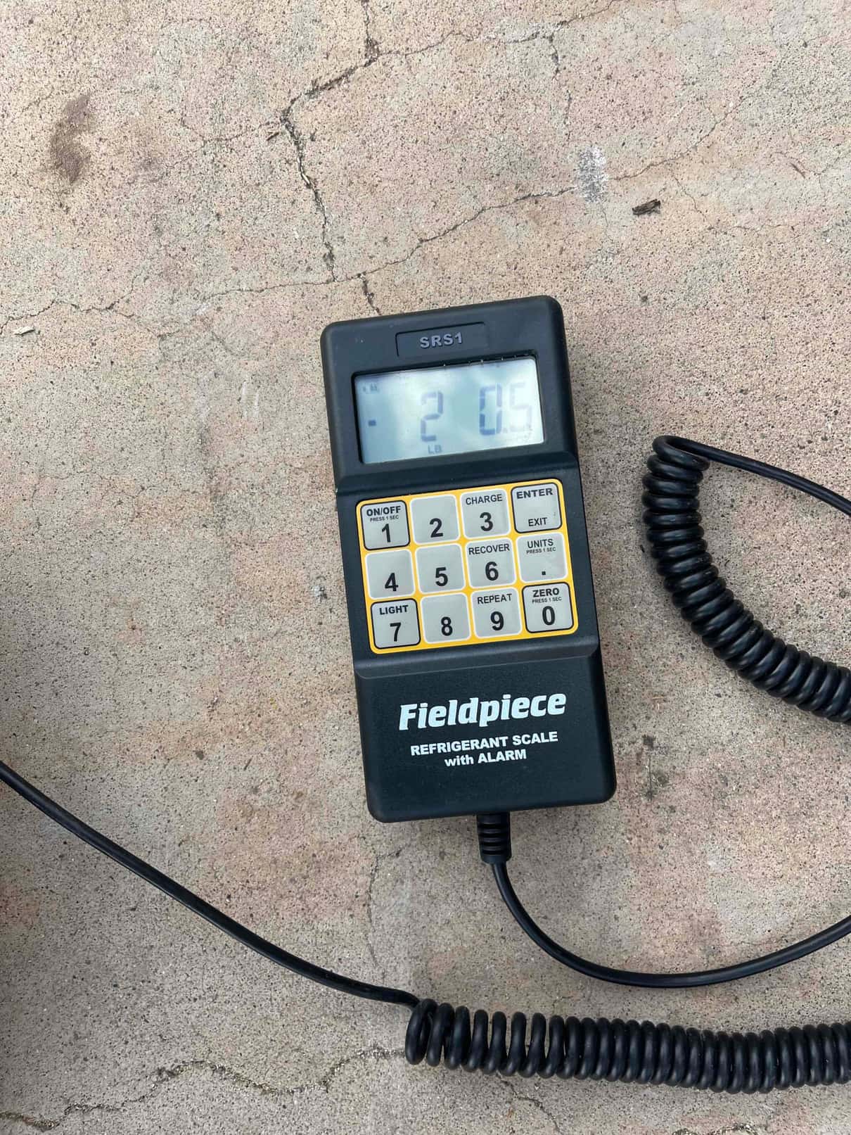 Digital refrigerant scale controller on the job site shows -2.05 lb during charging operations.