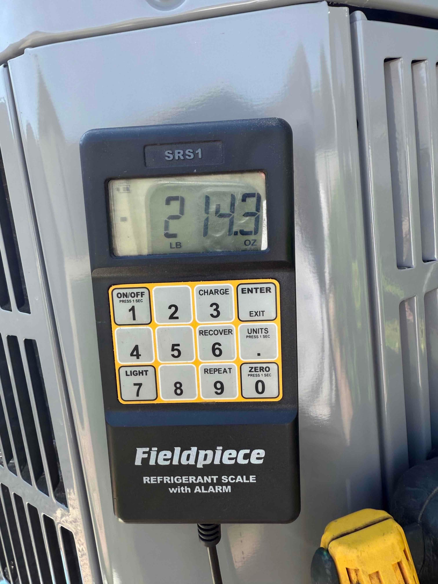 Digital refrigerant scale on the outdoor unit shows a charge amount of 2 pounds 14.3 ounces during system installation.