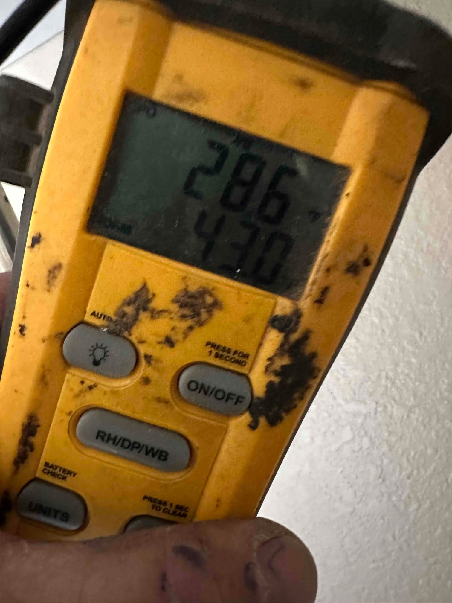 Digital thermometer displays 28.6 and 43.0 on screen while measuring air conditions during system commissioning.