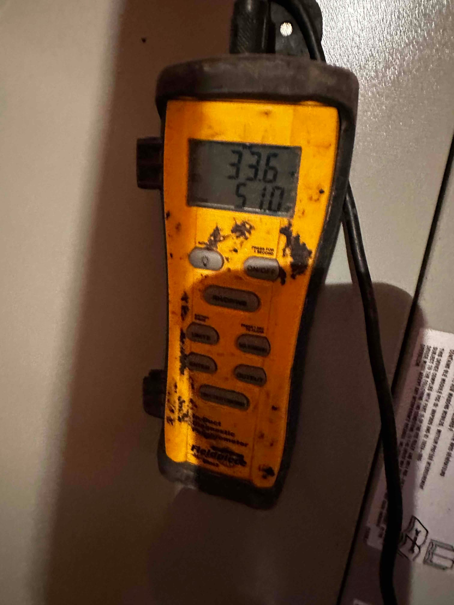 Digital thermometer displays 33.6 on the main line and 51.0 on the secondary line during air temperature checks at the air handler.