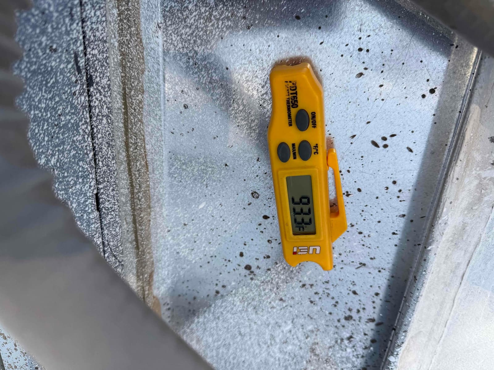 Digital thermometer displays 93.3°F while measuring air temperature inside the HVAC duct or plenum area.