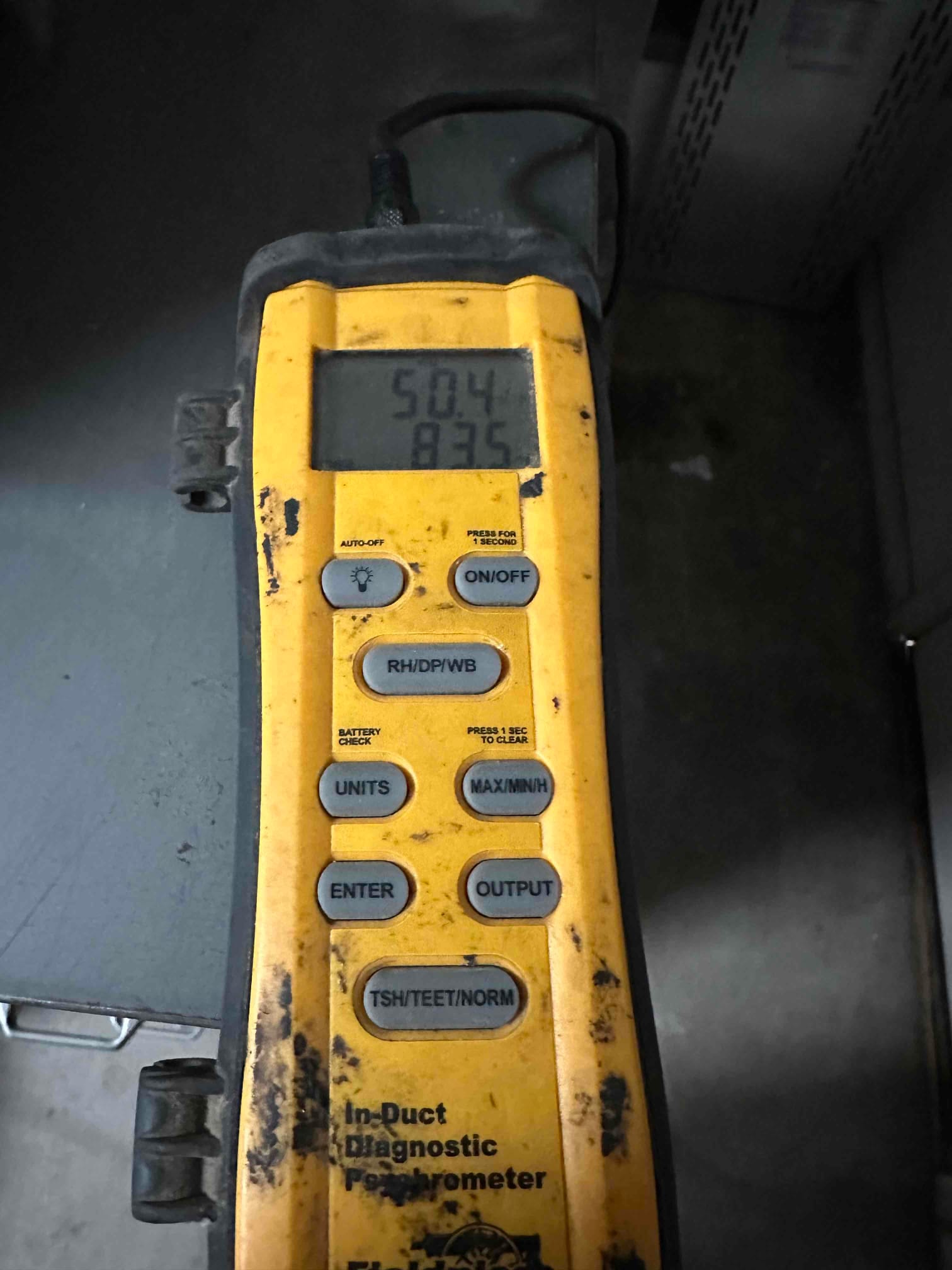 Digital thermometer probe reads 50.4 degrees Fahrenheit on the supply side during cooling performance verification.