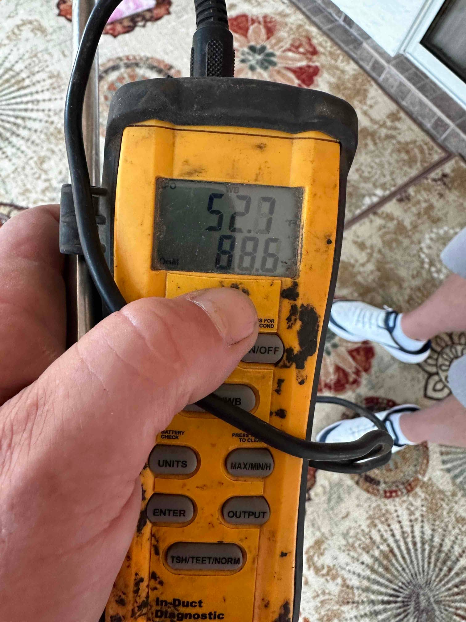 Digital thermometer shows 52.9°F, documenting cold supply air temperature during commissioning.