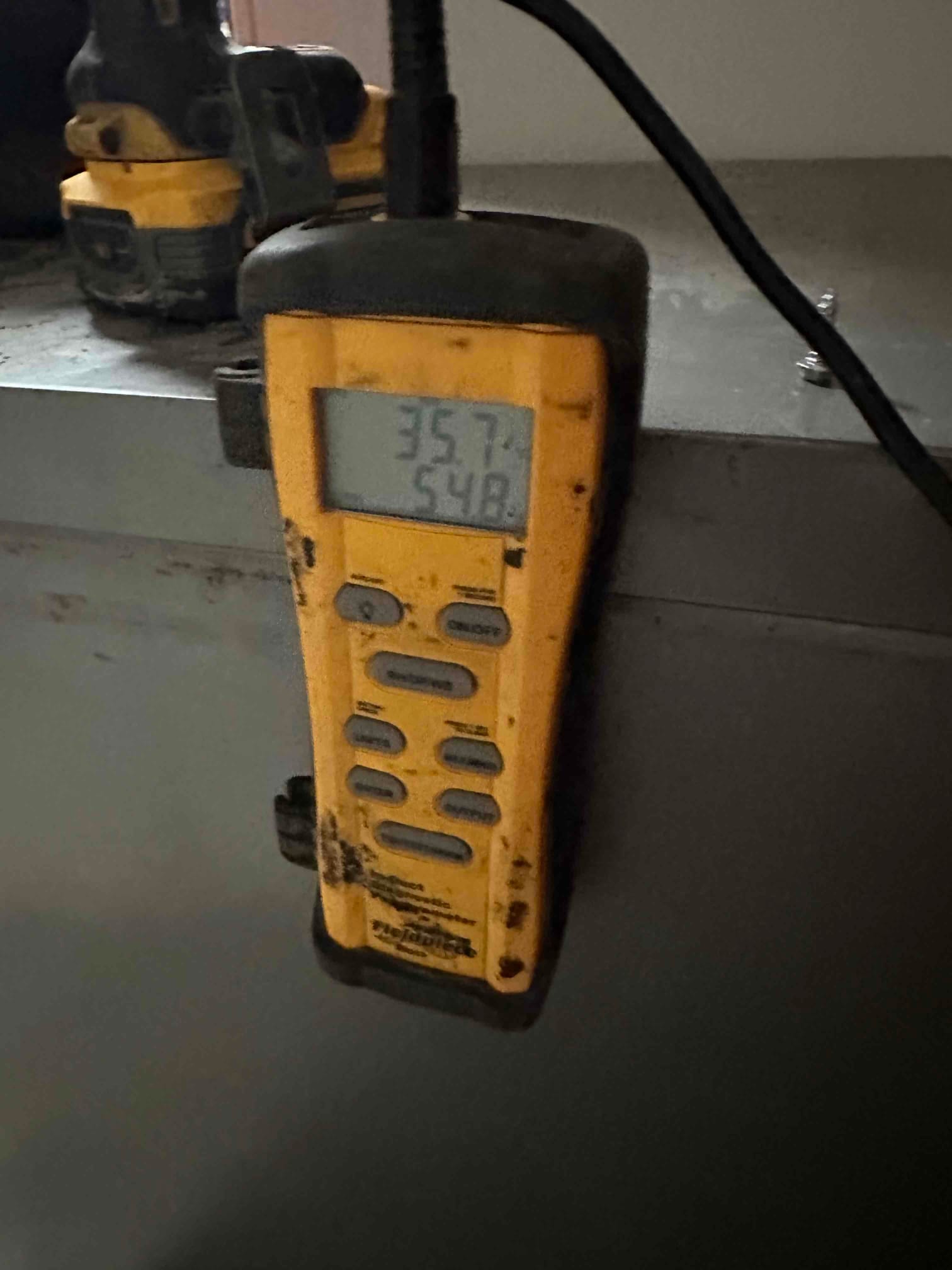 Digital thermometer shows 54.8 degrees on the lower display while measuring air temperature at the indoor unit.
