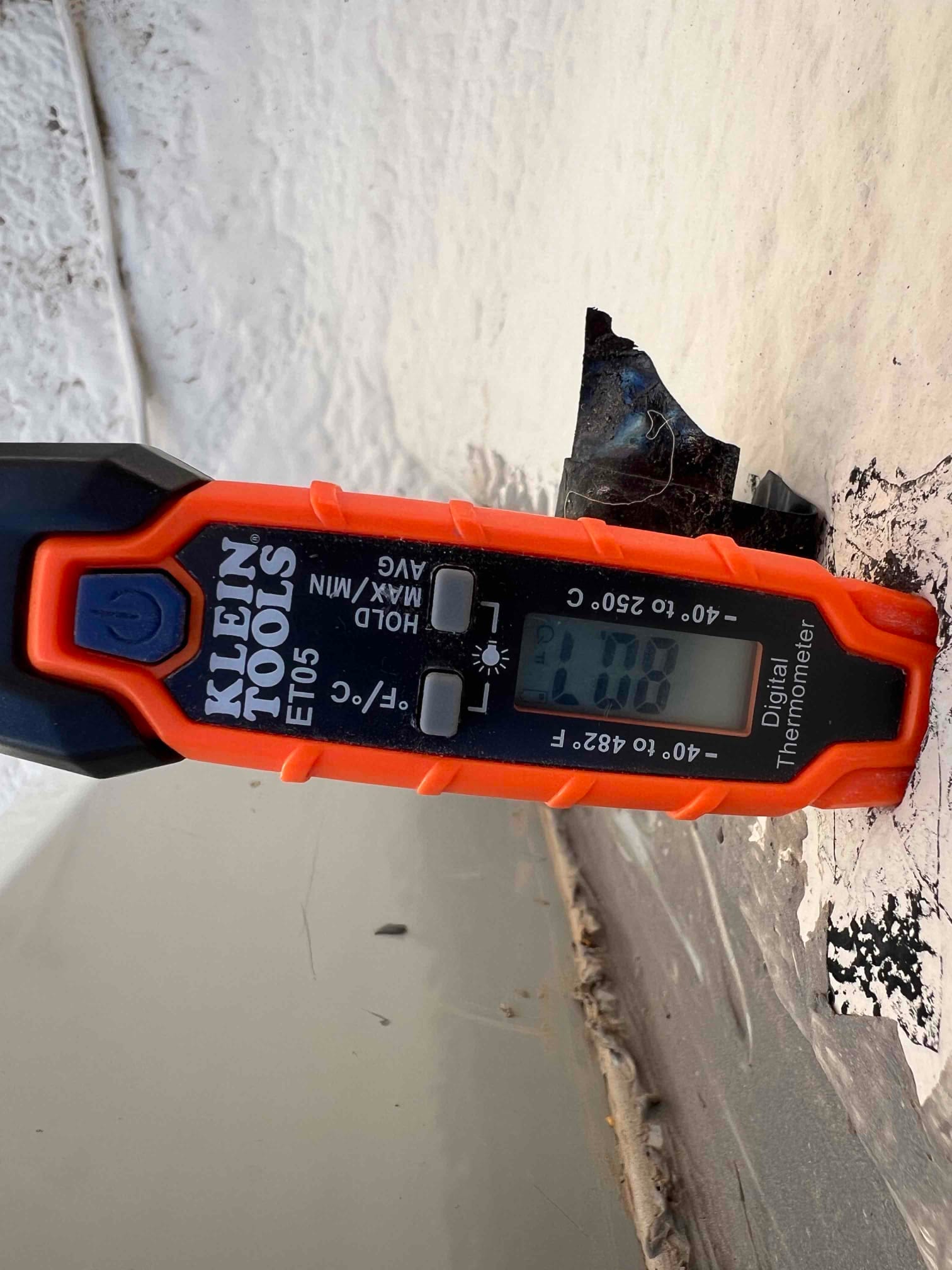 Digital thermometer shows 80.2 °F while measuring surface temperature at the repair site during the air conditioning service.