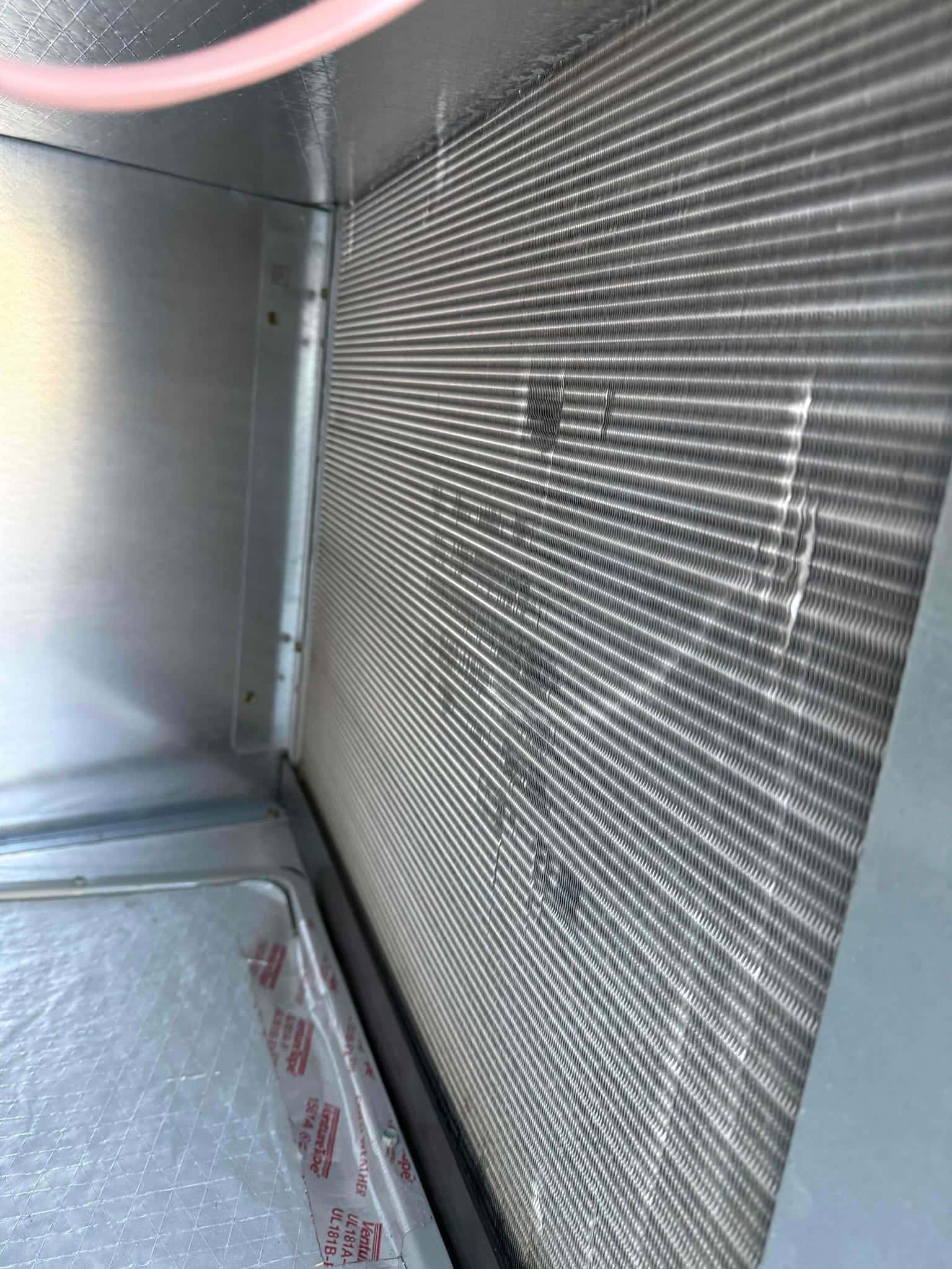 Evaporator coil inside an air handler cabinet, showing clean aluminum fins and surrounding sheet-metal interior surfaces.