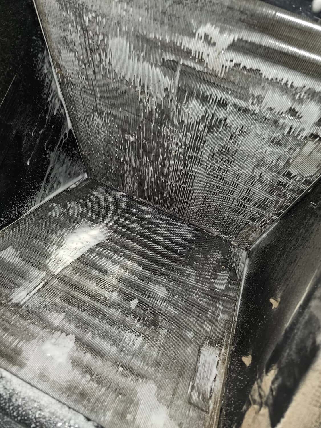 Evaporator coil surfaces inside an air handler with cleaning foam residue across the aluminum fins.