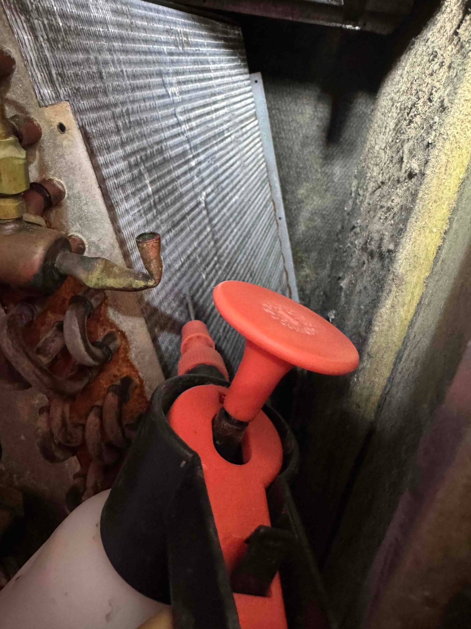 Evaporator coil and surrounding housing are visible, with a nearby pump sprayer wand positioned in the service area.