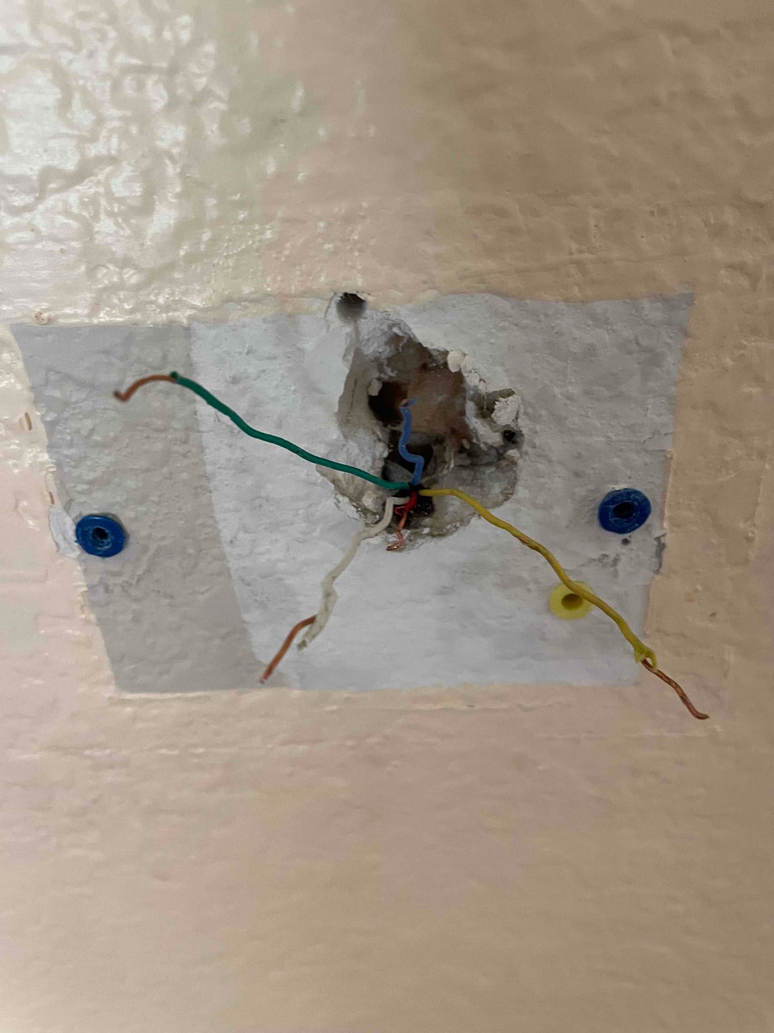 Exposed low-voltage thermostat control wires extend from a wall opening with drywall anchors visible on both sides.