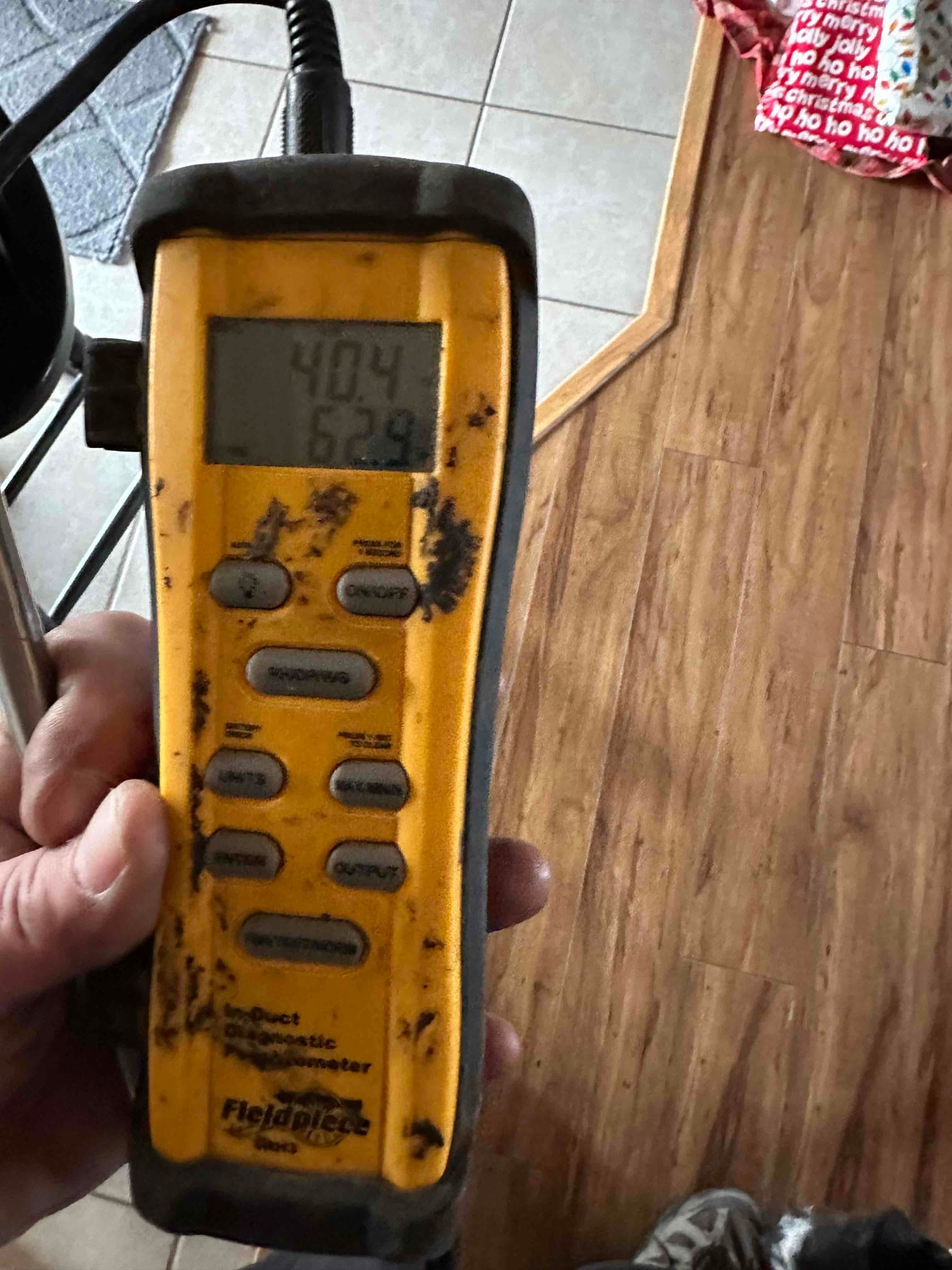 Handheld digital thermometer shows 62.9 degrees Fahrenheit, documenting air temperature during HVAC supply and return checks.