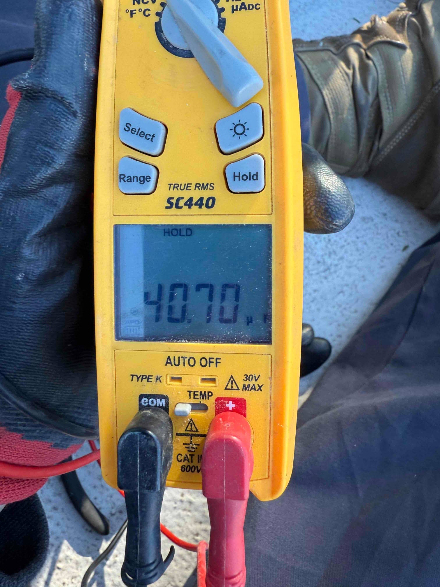 Multimeter measures capacitance with test leads connected, displaying 40.70 µF on the HOLD screen.