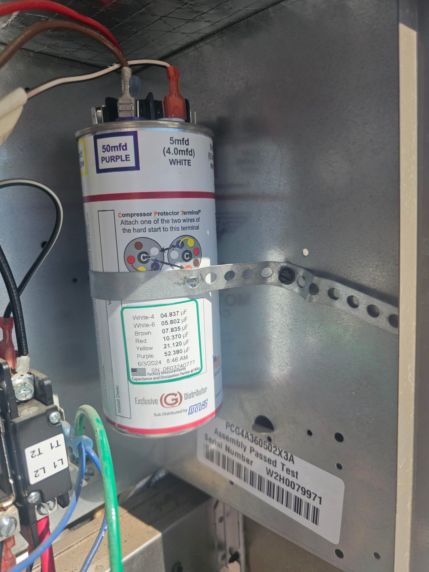 New dual-run capacitor installed in condenser control compartment, labeled 50 mfd purple and 5 mfd white, secured with metal strap.