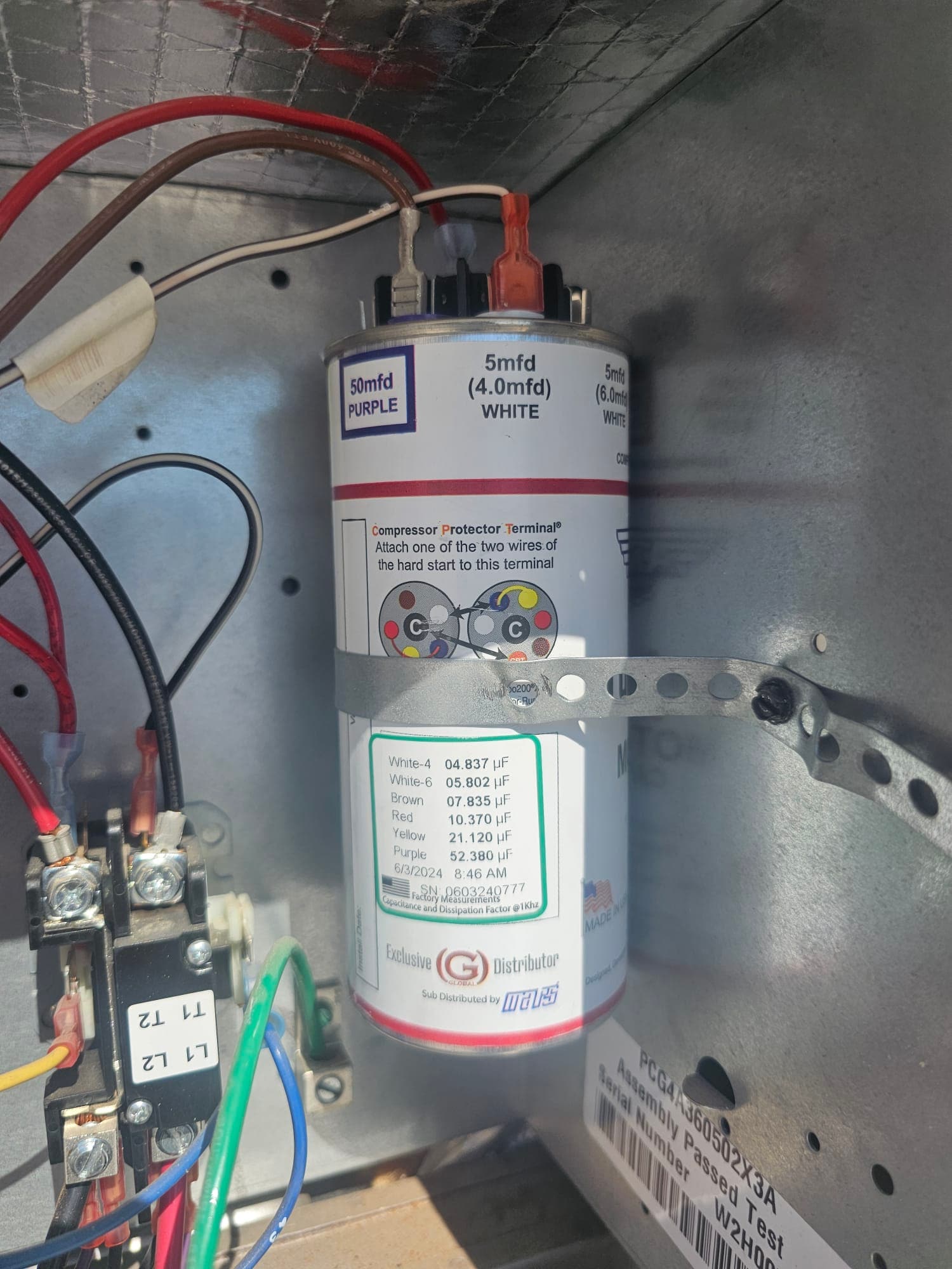New dual-run capacitor installed in condenser panel, labeled 50 mfd PURPLE and 5 mfd WHITE, secured with a metal strap.