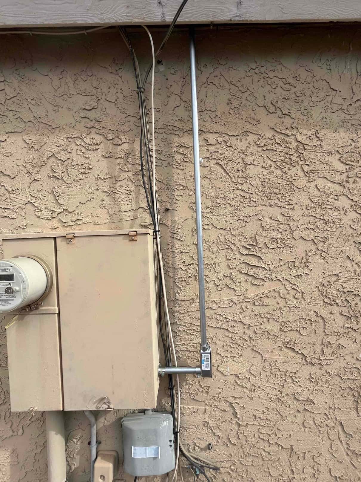 New exterior electrical conduit and junction box installed near the service panel for the HVAC package unit connection.