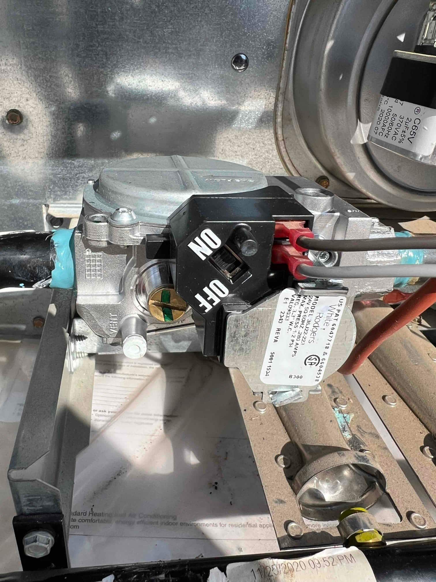 New furnace gas control valve installed with ON/OFF knob and connected wiring and gas line visible inside the burner compartment.