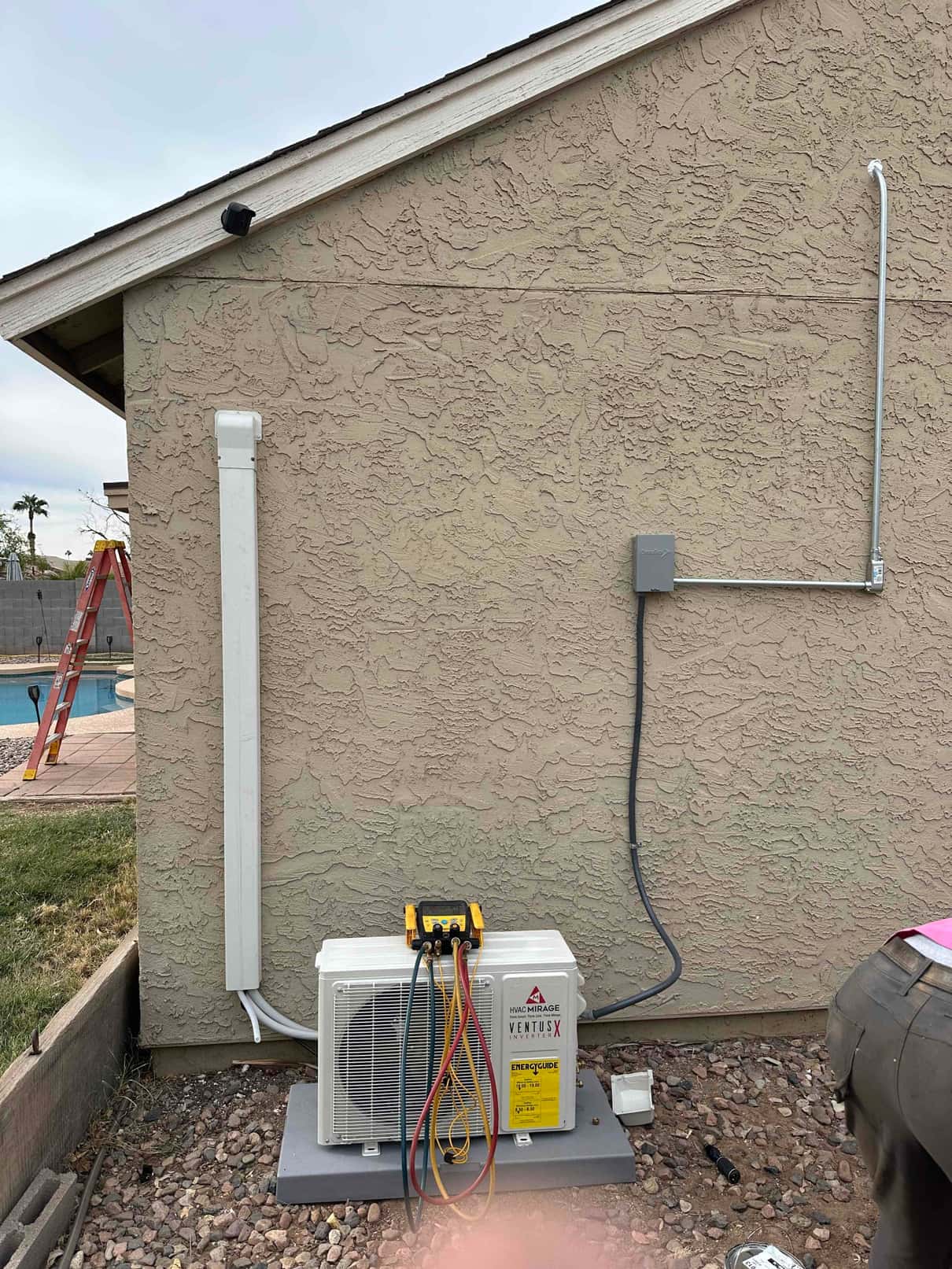 New mini-split outdoor unit set on a level pad with line-set cover, electrical whip, and disconnect installed on exterior wall.