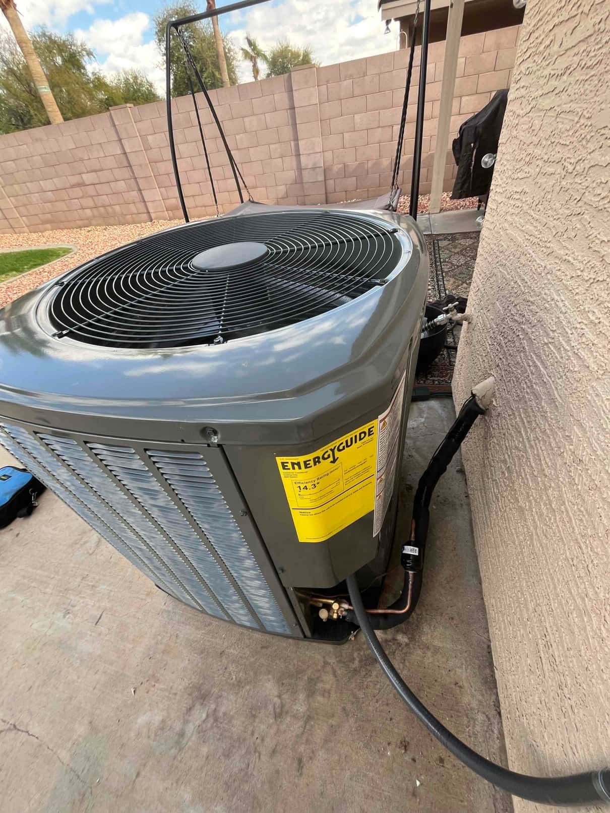 New outdoor condenser set on a concrete pad with insulated refrigerant lines and sealed wall penetration.