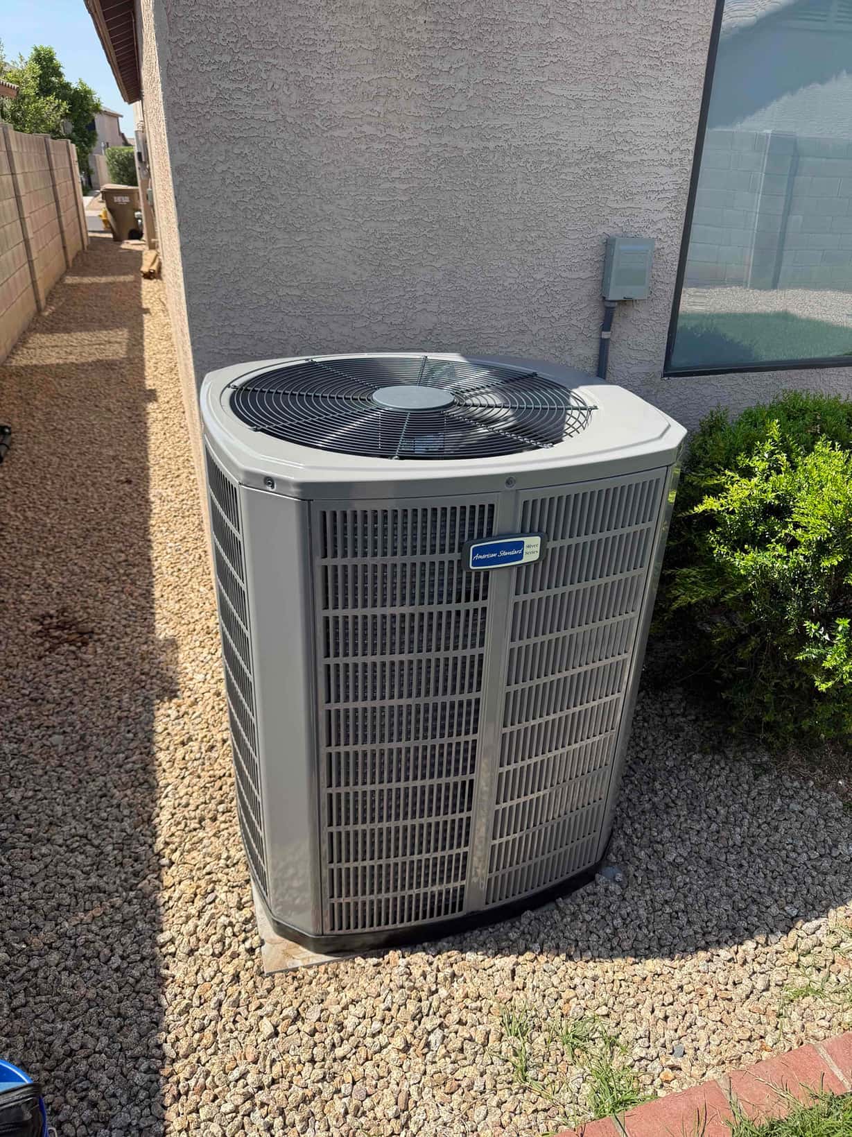 New outdoor condenser set on a level pad beside the house with nearby disconnect and trimmed landscaping.